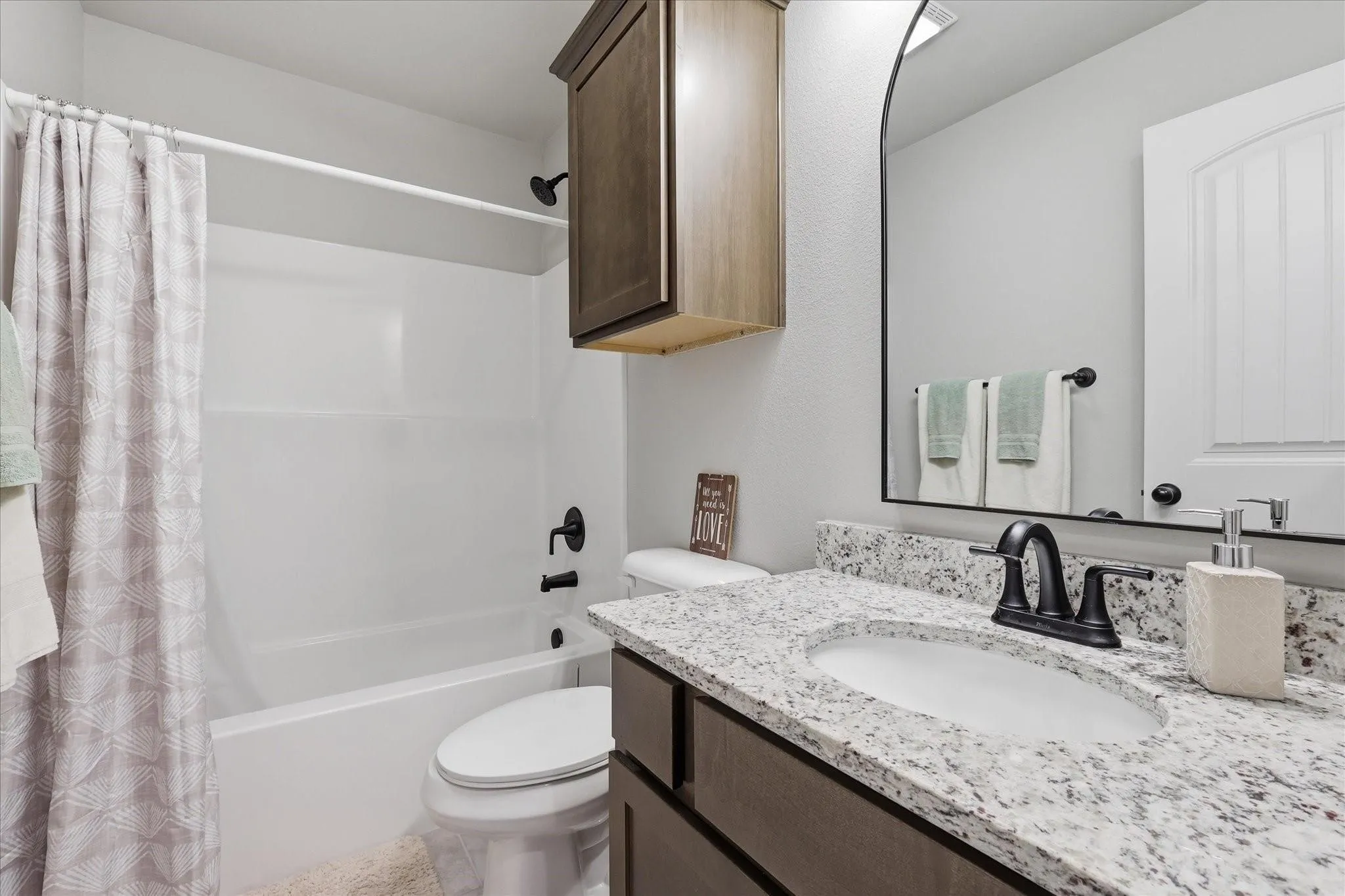 White bathtub and shower combination with matte black fixtures