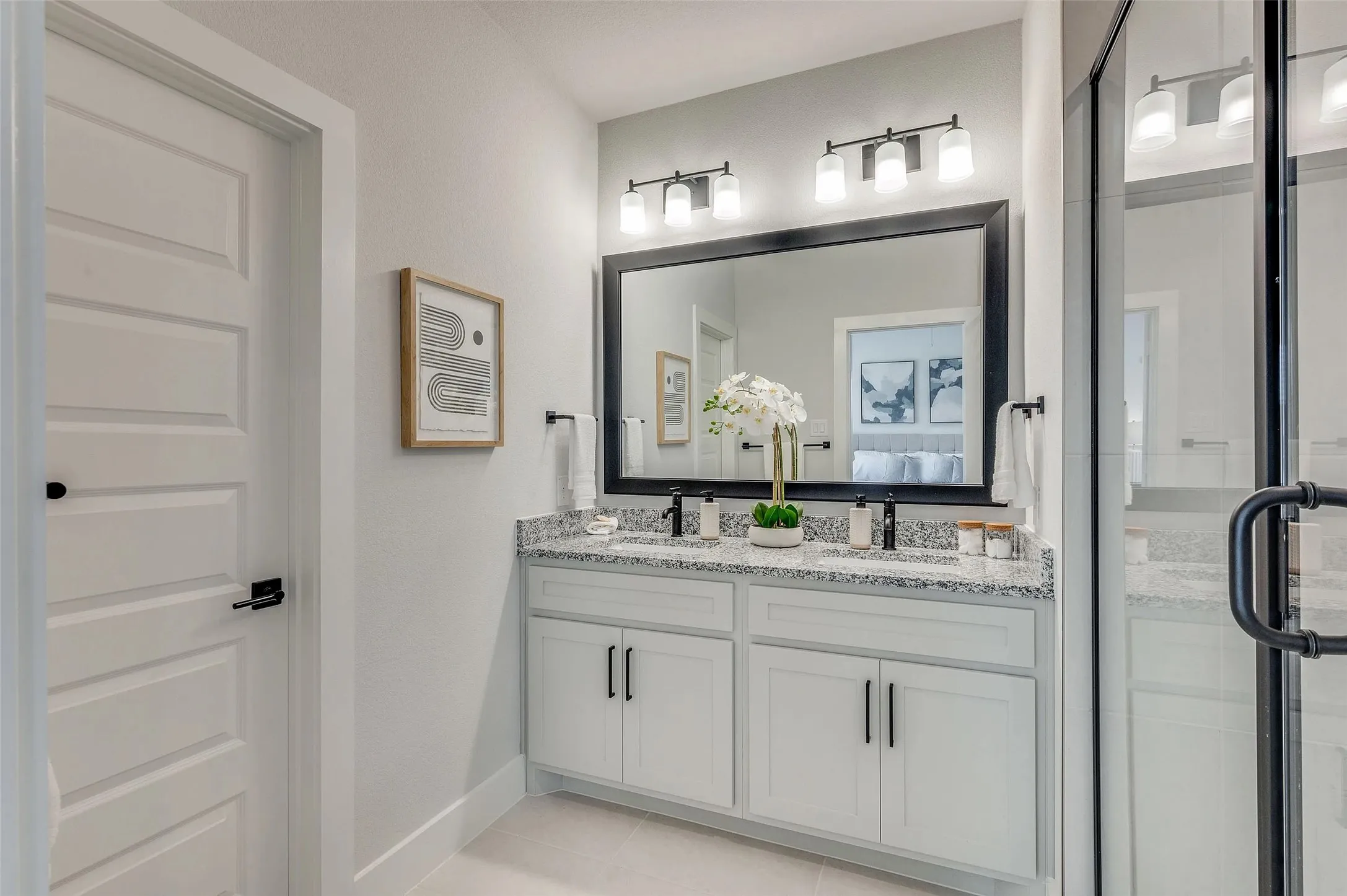Double vanity with granite countertop, white cabinetry, and matte black hardware