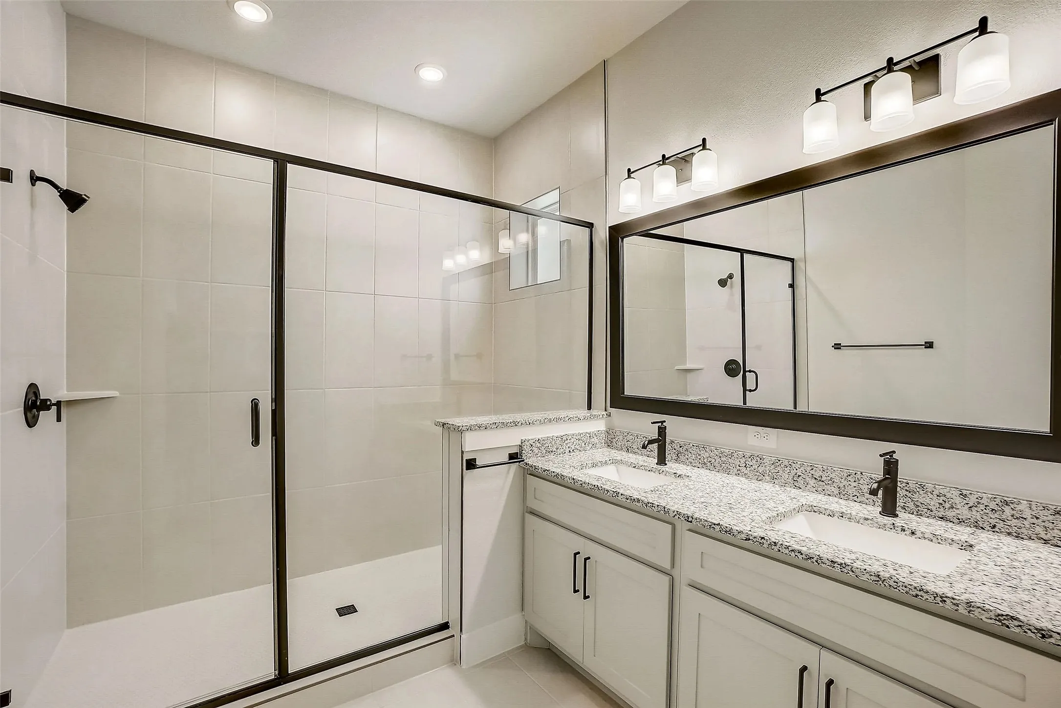 Dual vanity with stone-finish countertops, undermount sinks, and matte black fixtures