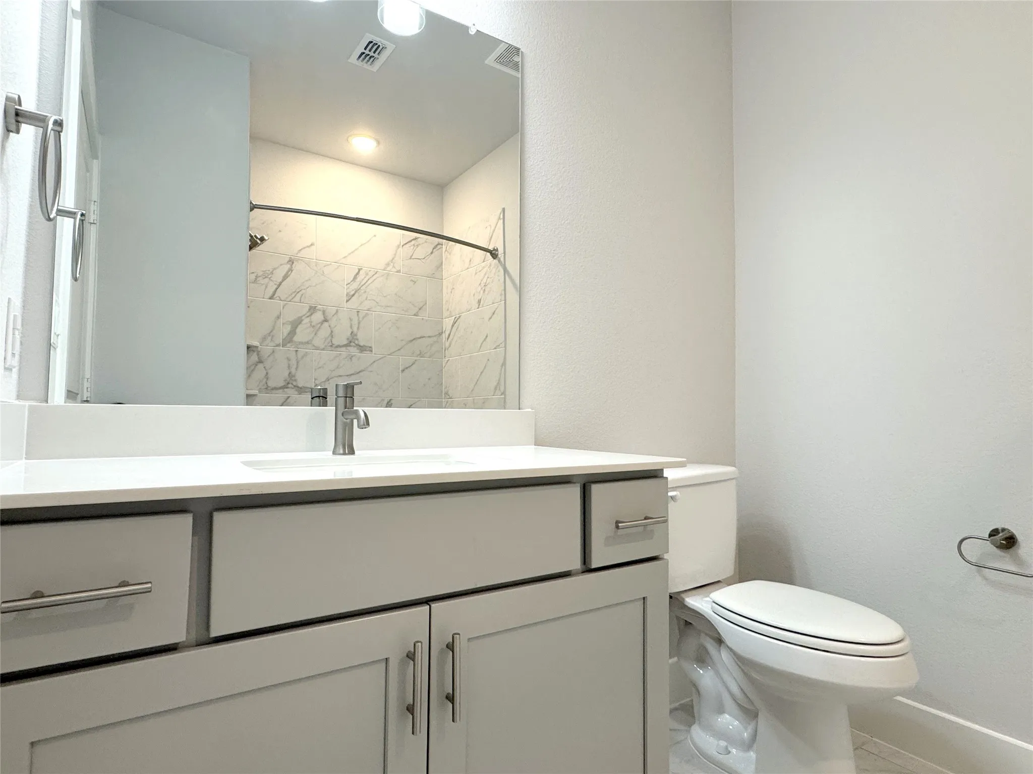 Bathroom featuring a light gray vanity with white countertop, undermount sink, and brushed nickel fixtures
