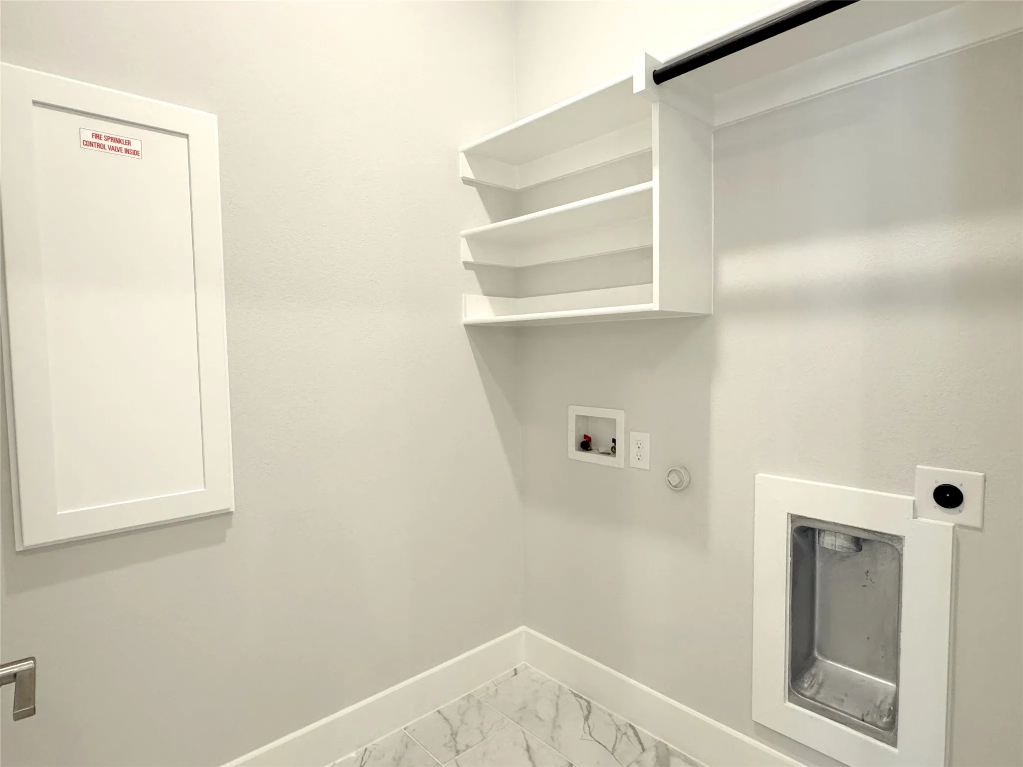 Laundry area featuring built-in shelving, a black hanging rod, wall-mounted connections for appliances, and a utility sink