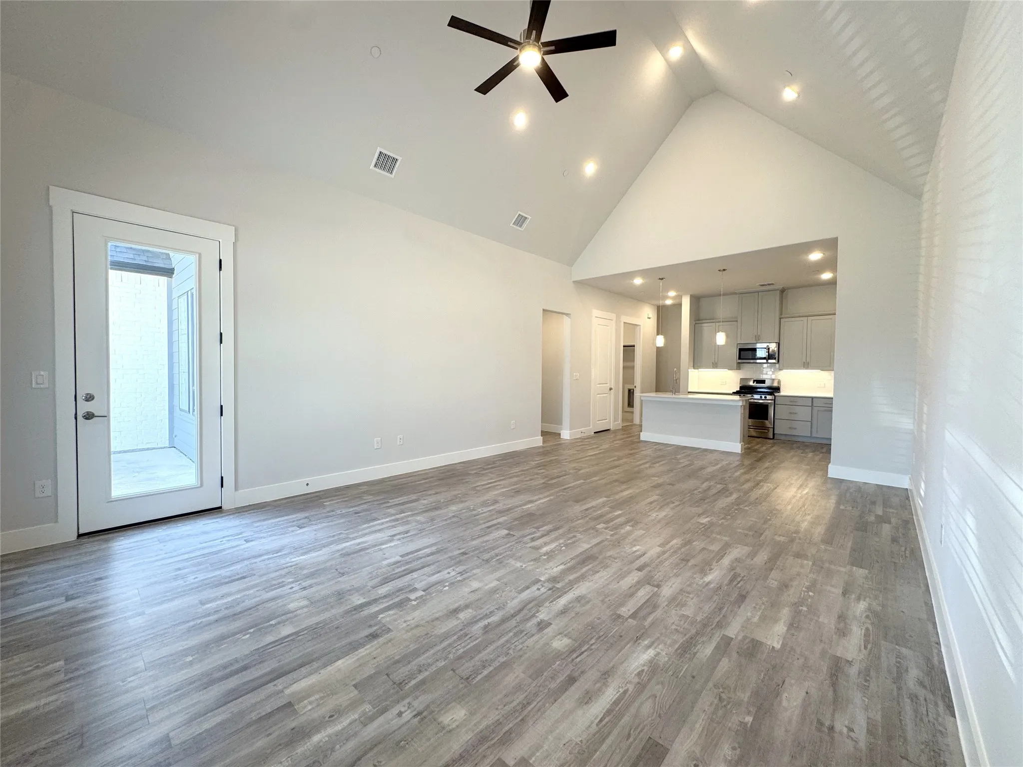 Spacious living area featuring high vaulted ceilings, recessed lighting, and wood-finish flooring