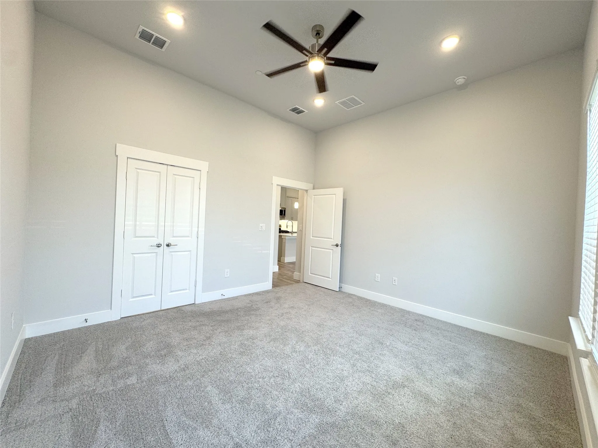 Spacious room featuring vaulted ceilings, recessed lighting, a ceiling fan, light gray carpeting, and white trim
