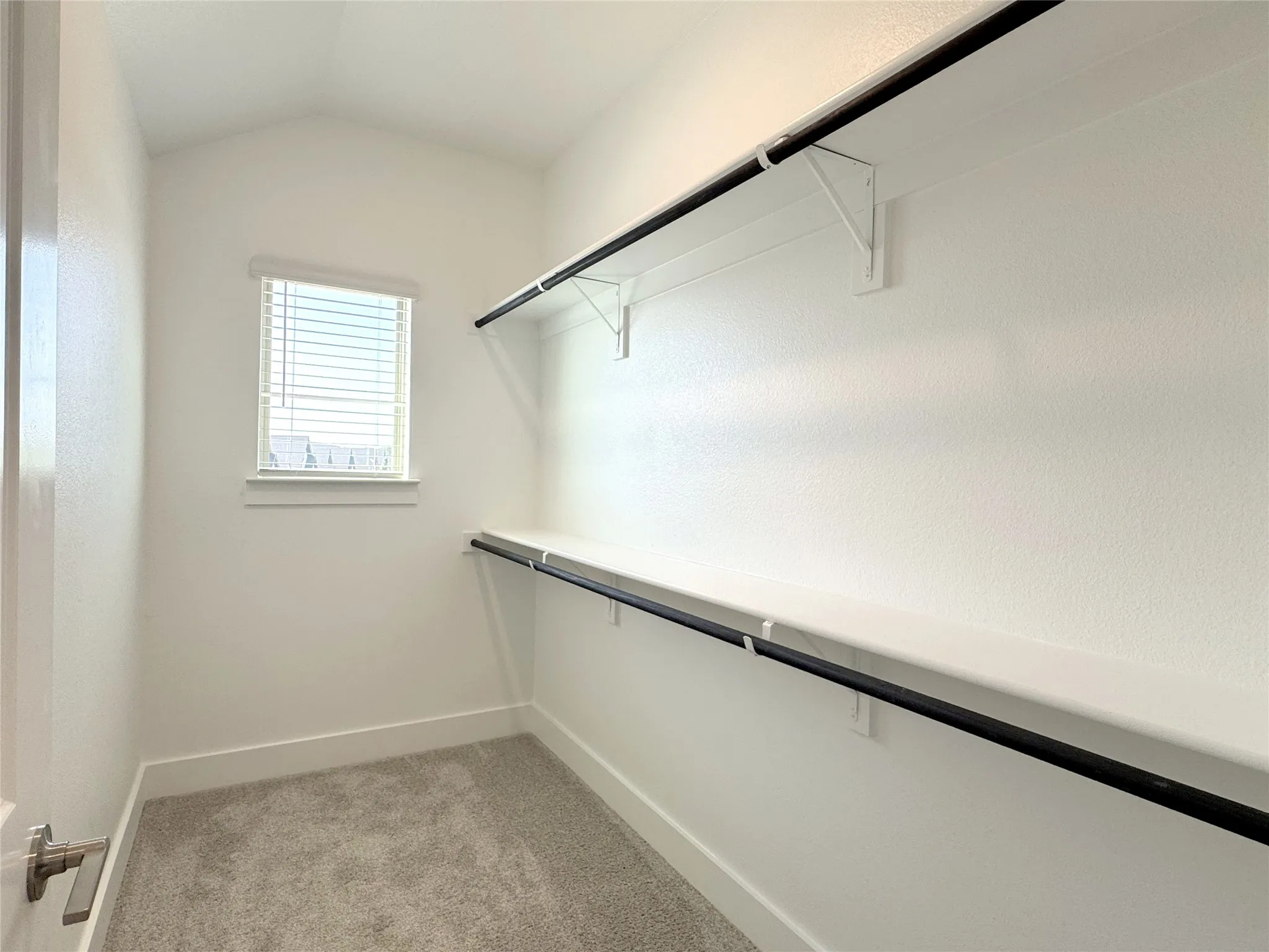 Walk-in closet with upper shelving and hanging rods