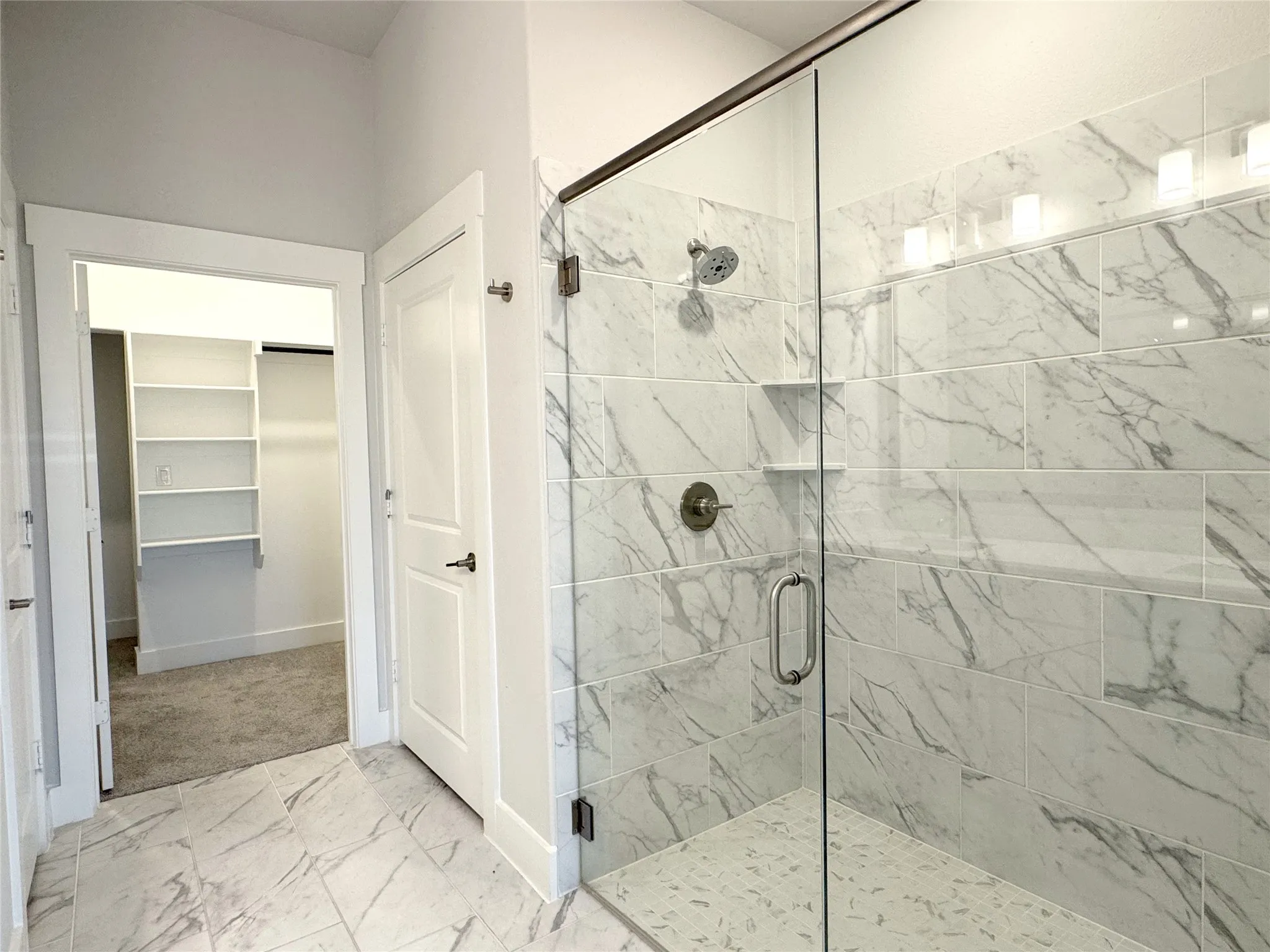 Glass-enclosed shower with subway-tiled walls and a rainfall showerhead