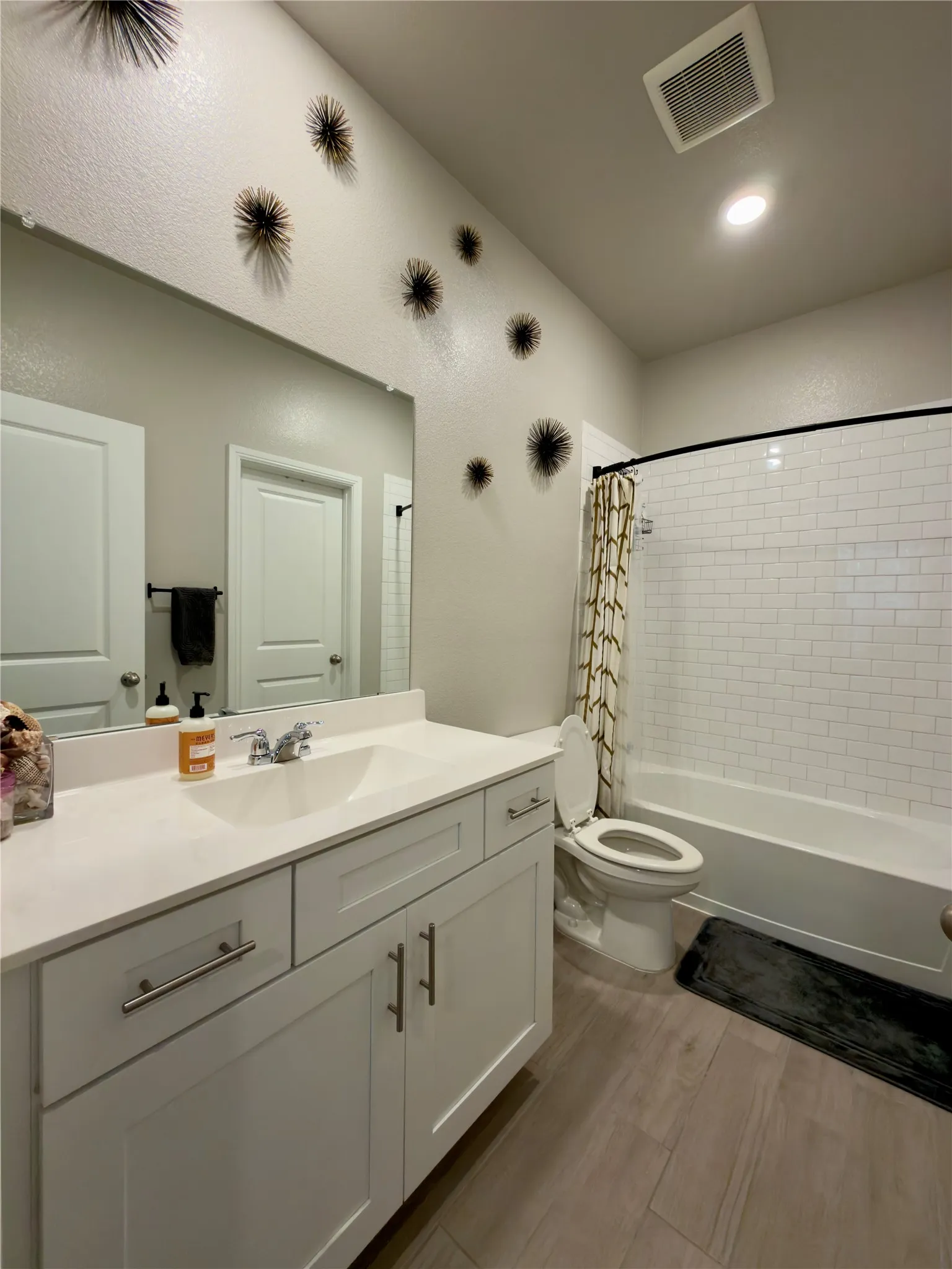 Bathroom with vanity, shower / tub combo with curtain, and light wood finished floors