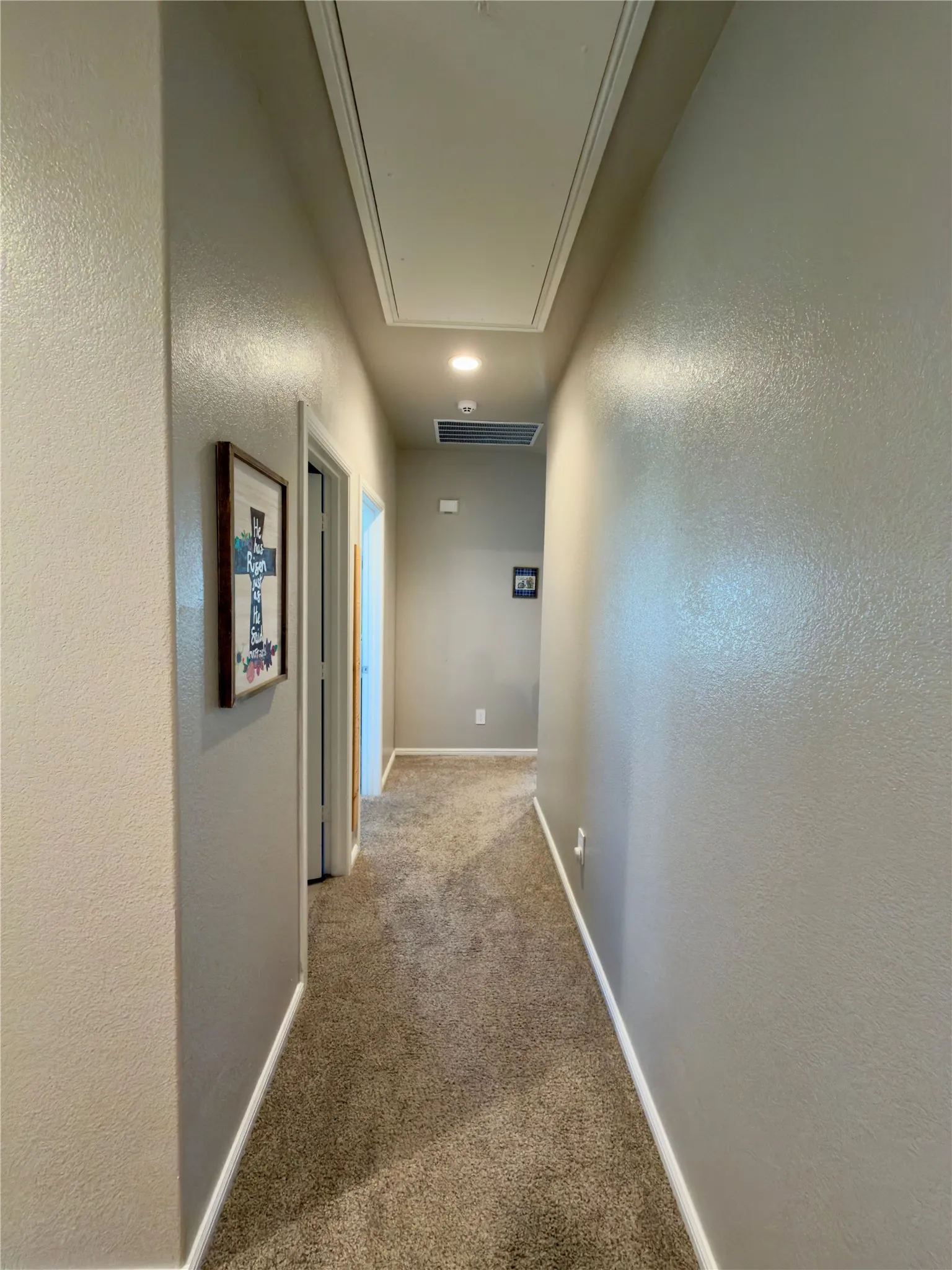 Corridor with a textured wall, carpet floors, and recessed lighting