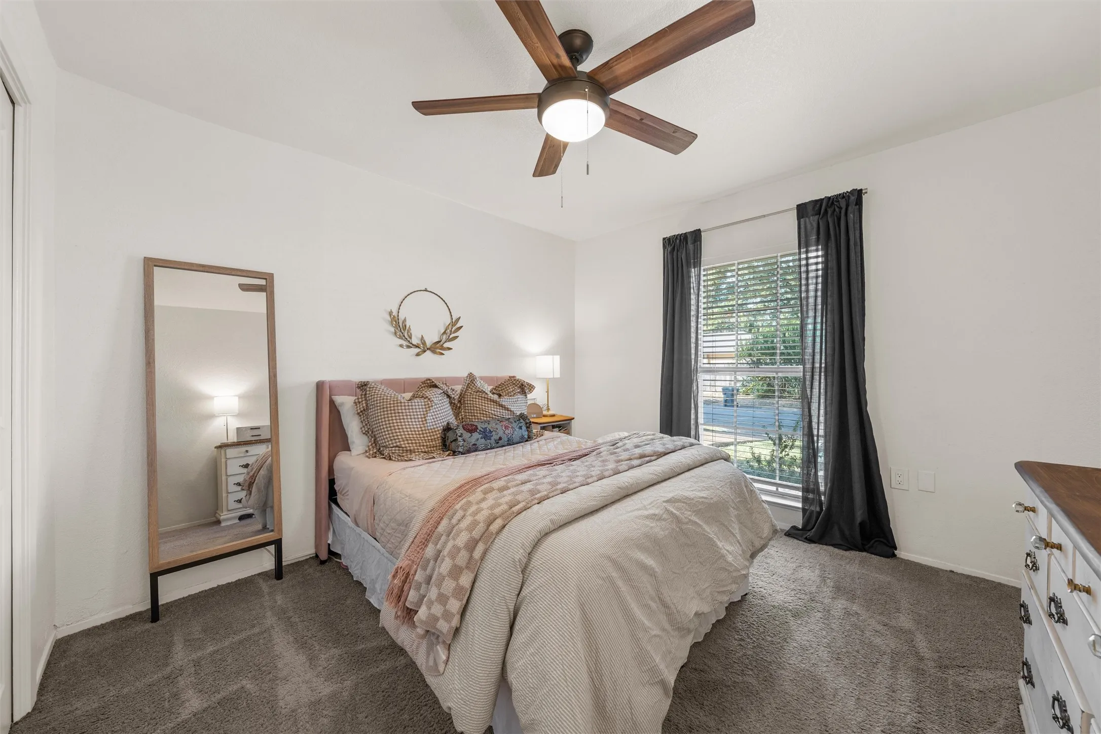 Neutral wall paint, ceiling fan with integrated lighting, window with blinds, carpeted flooring