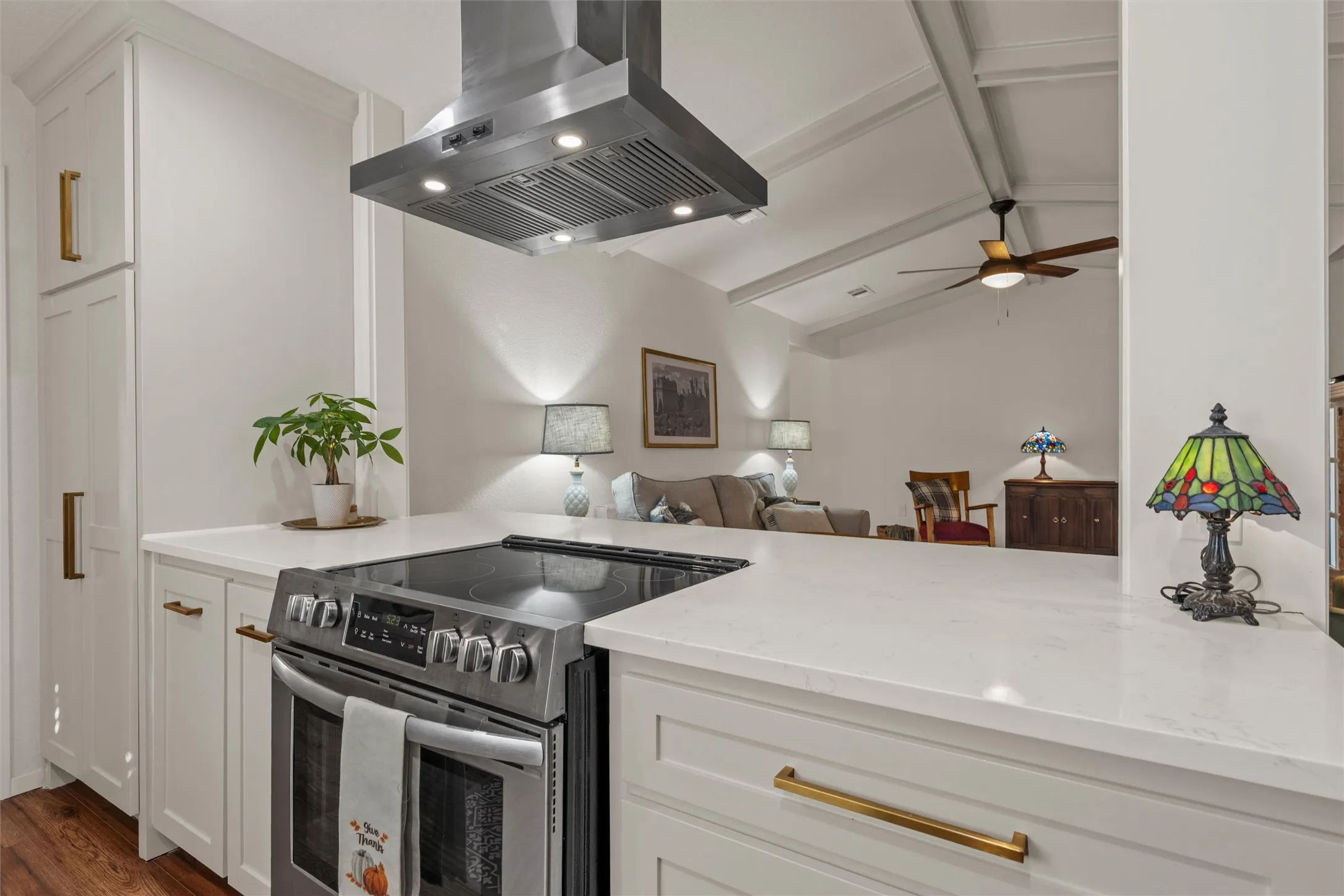 Stainless steel range with a coordinating range hood, white cabinetry, and light-toned countertops