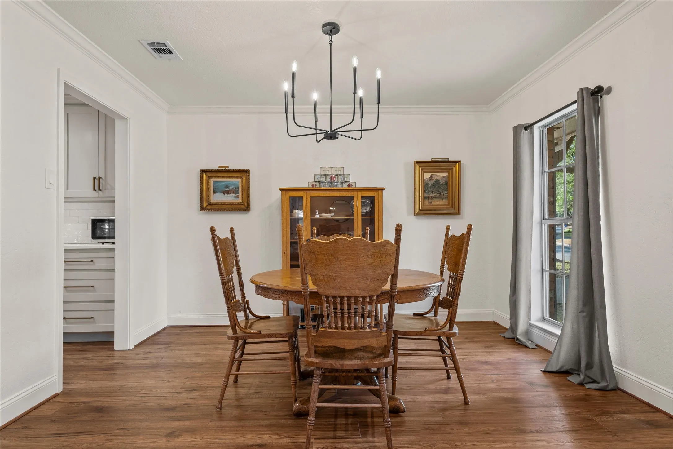 Wood-finish flooring throughout, crown molding, and a modern black chandelier