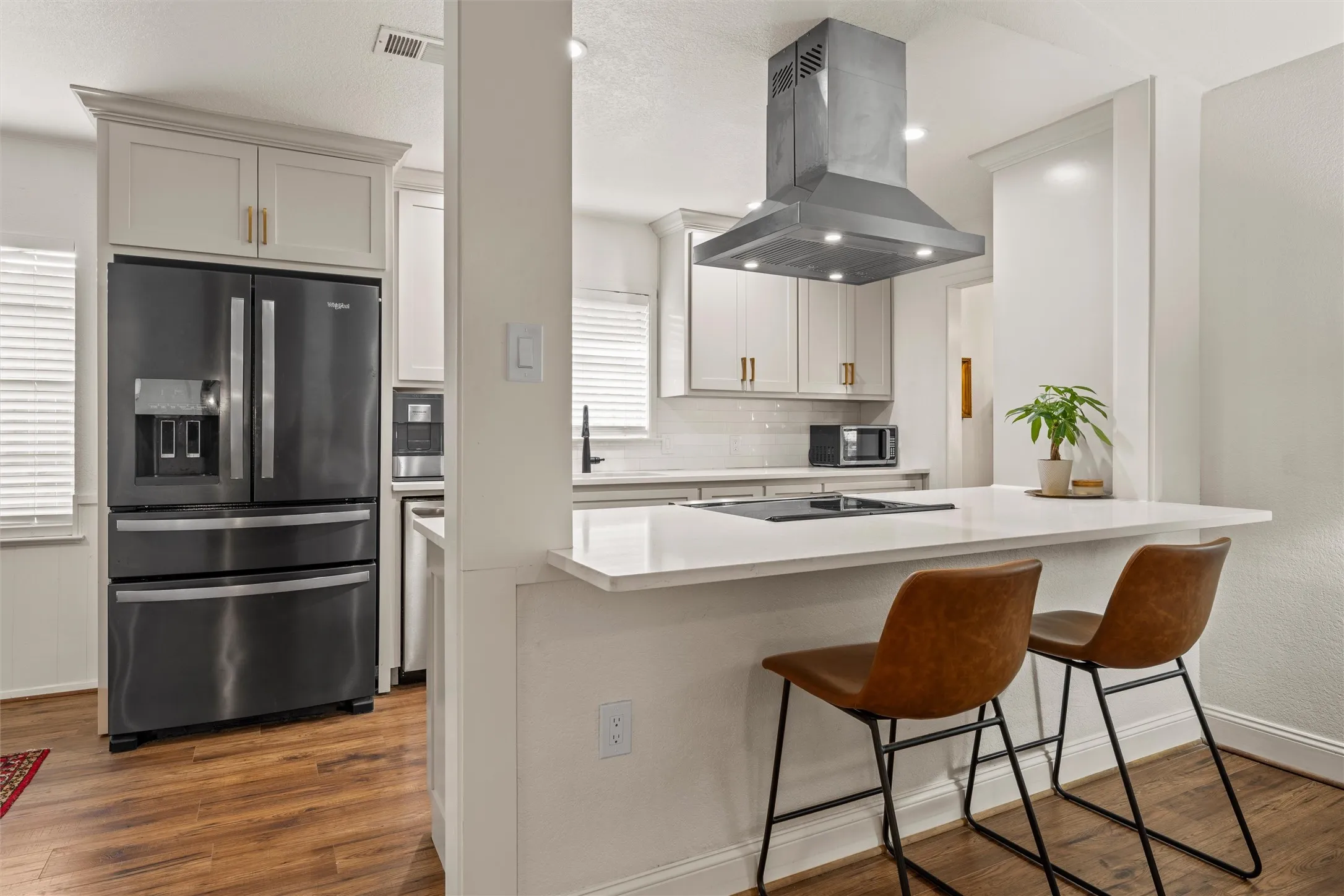 Kitchen featuring wood-finish flooring, light-toned cabinetry, stainless steel range hood, built-in cooktop, and a white countertop