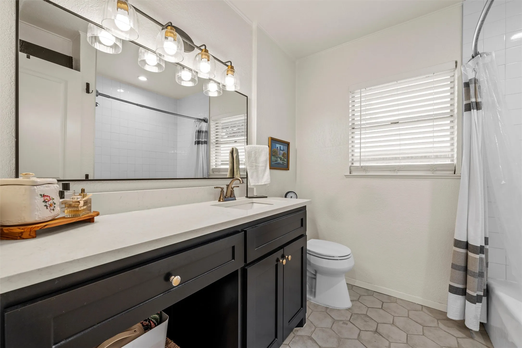 Bathroom featuring a dark wood-finish vanity with a light-toned countertop, a rectangular mirror, and a five-light fixture