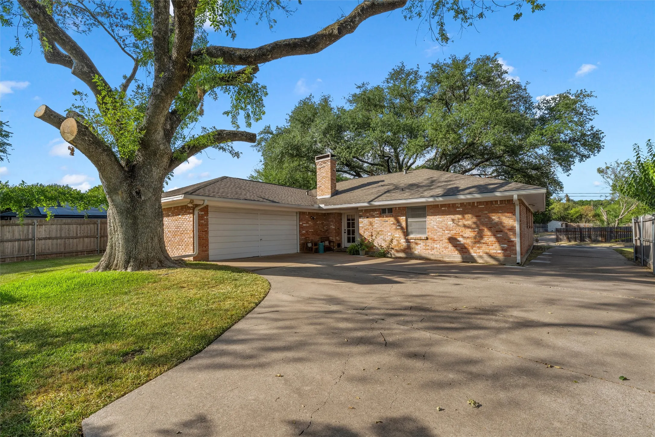 Brick exterior with a shingled roof, attached garage, and a concrete driveway