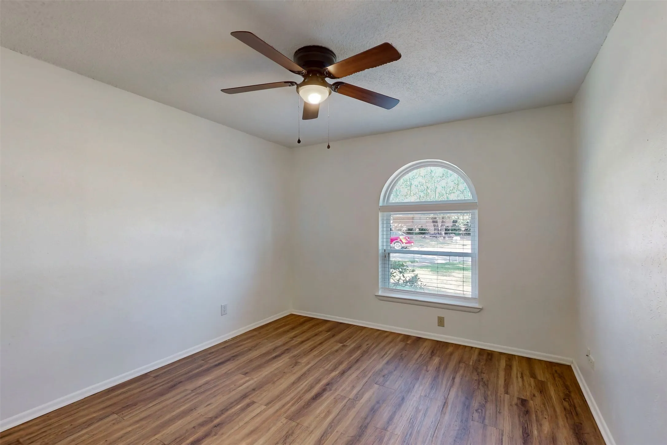 Bedroom 2 has a window arch, ceiling fan and a view of the front yard.