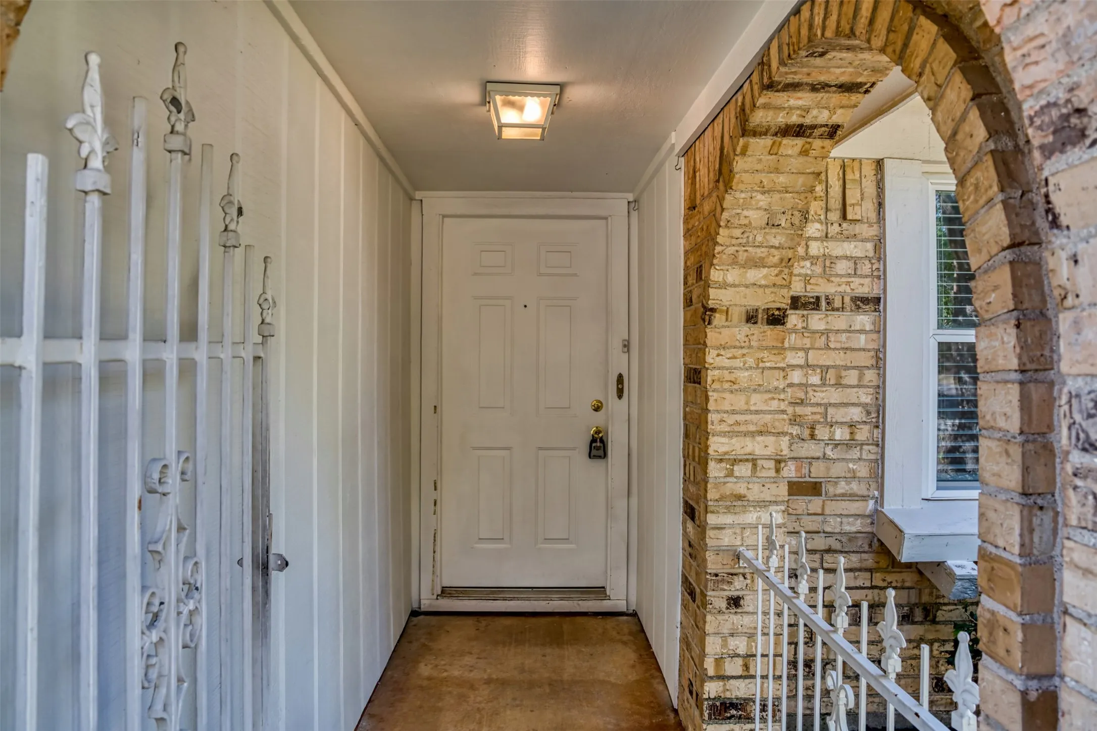 Decorative features greet you at the front door with this brick arch and elegant metal fencing.