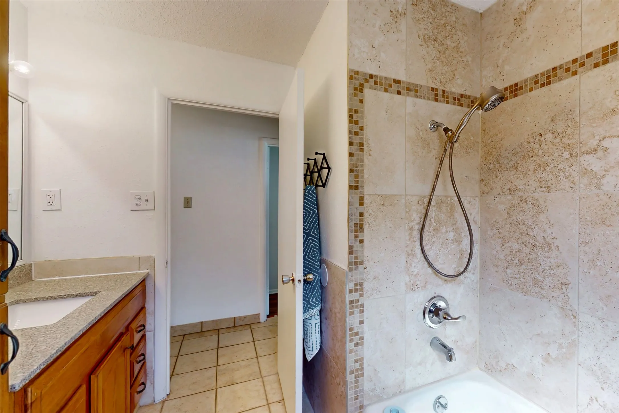Ceramic tile surrounds this shower and bathroom. Built-in towel rack behind the door conveys.