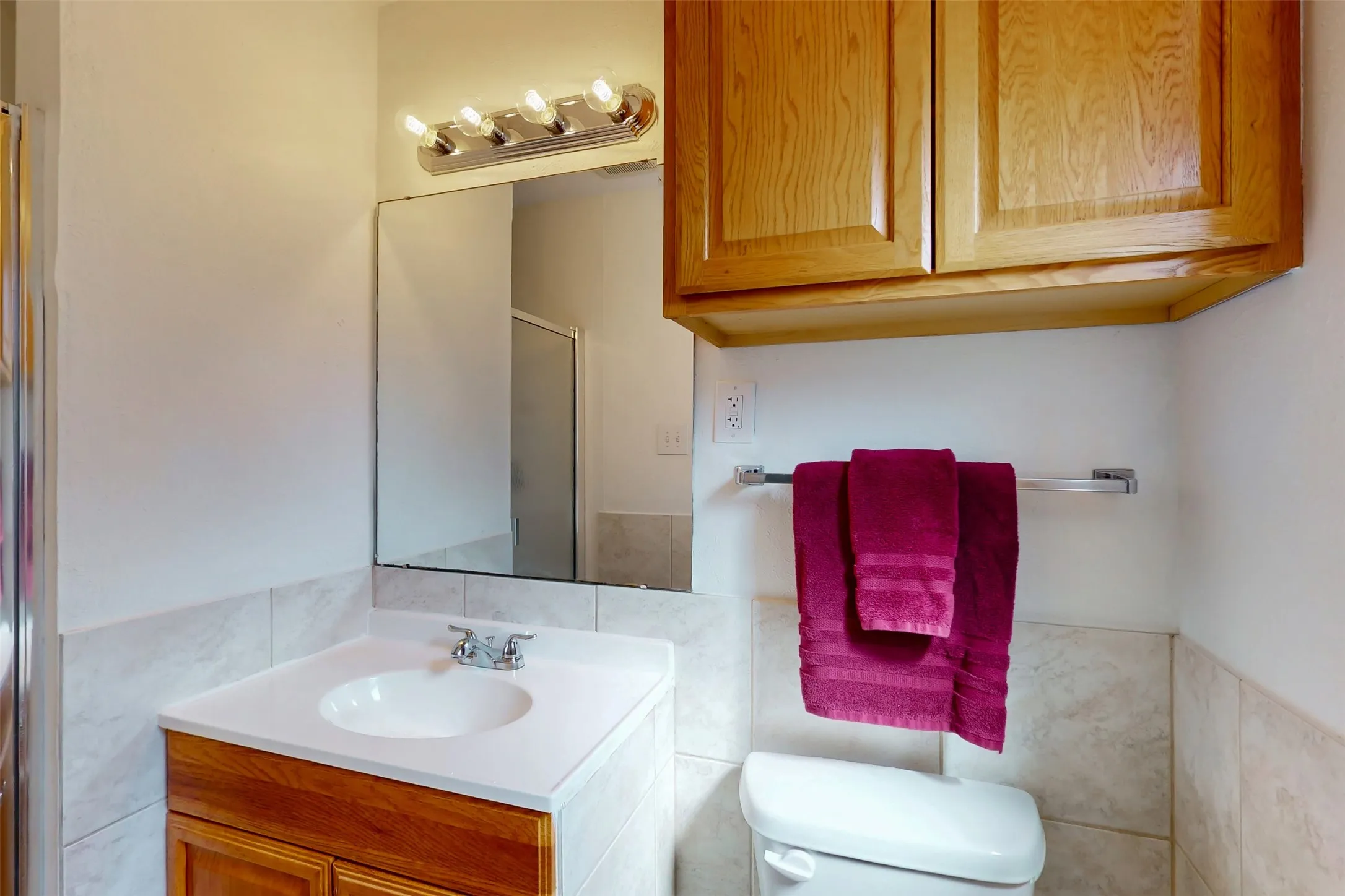 Primary bathroom features built-in storage vanity and upper cabinet for linens and toiletries.