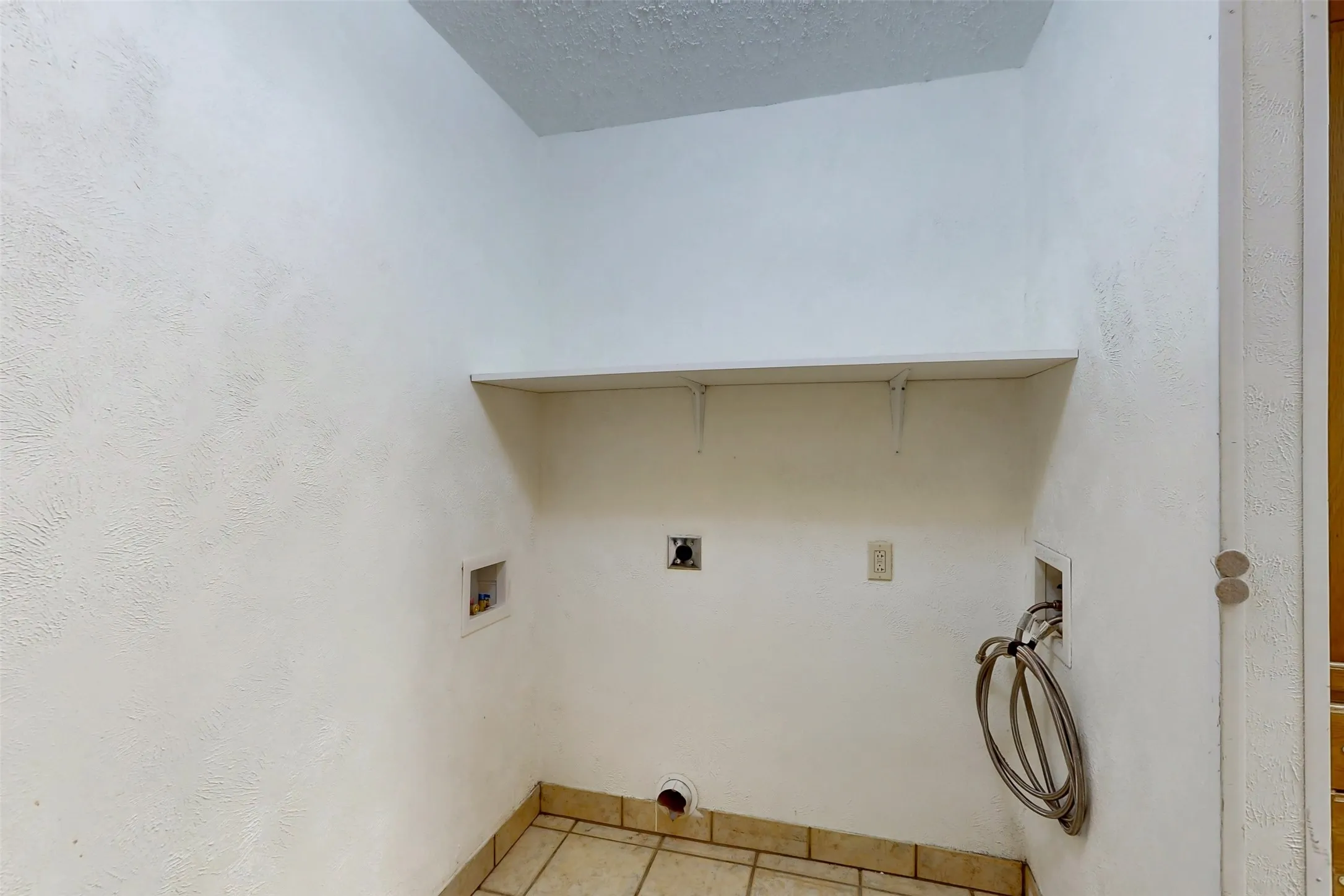 Utility room is conveniently located near the kitchen. Water supply provided on right and newer washer drain on left.