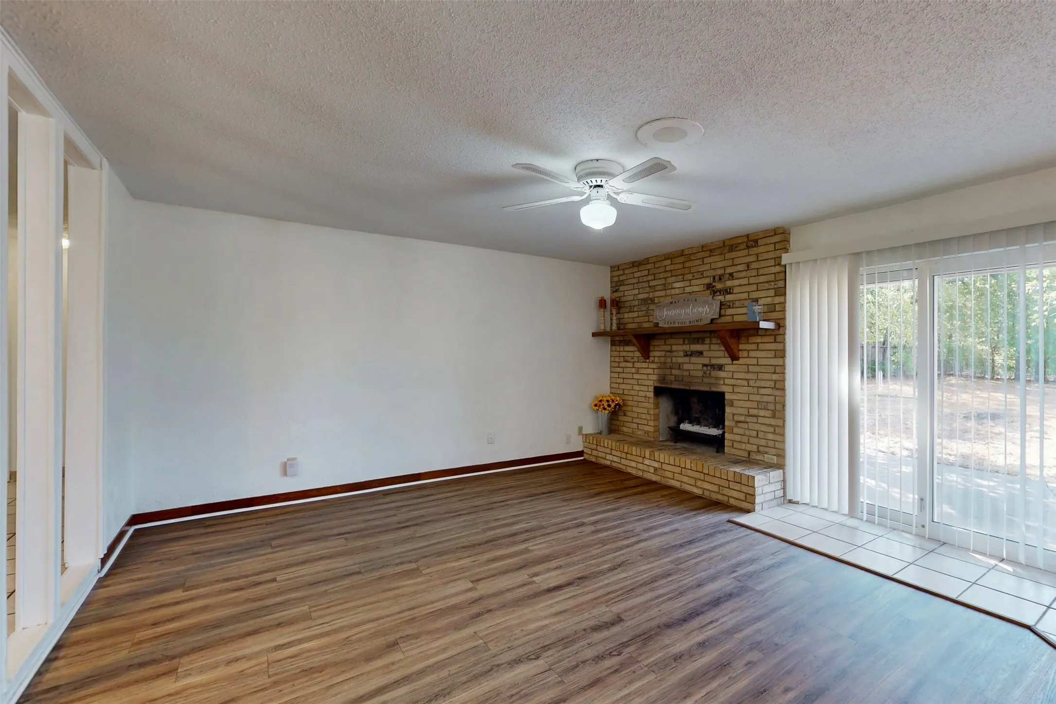 Spacious living area has a brick wood-burning fireplace with a raised hearth and wood mantle!