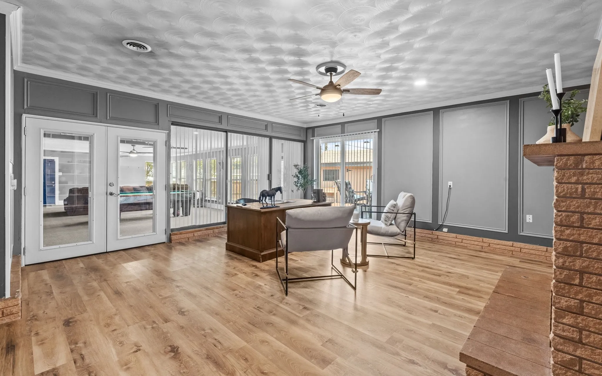 Wood-finish flooring throughout, with decorative wall paneling and a brick fireplace