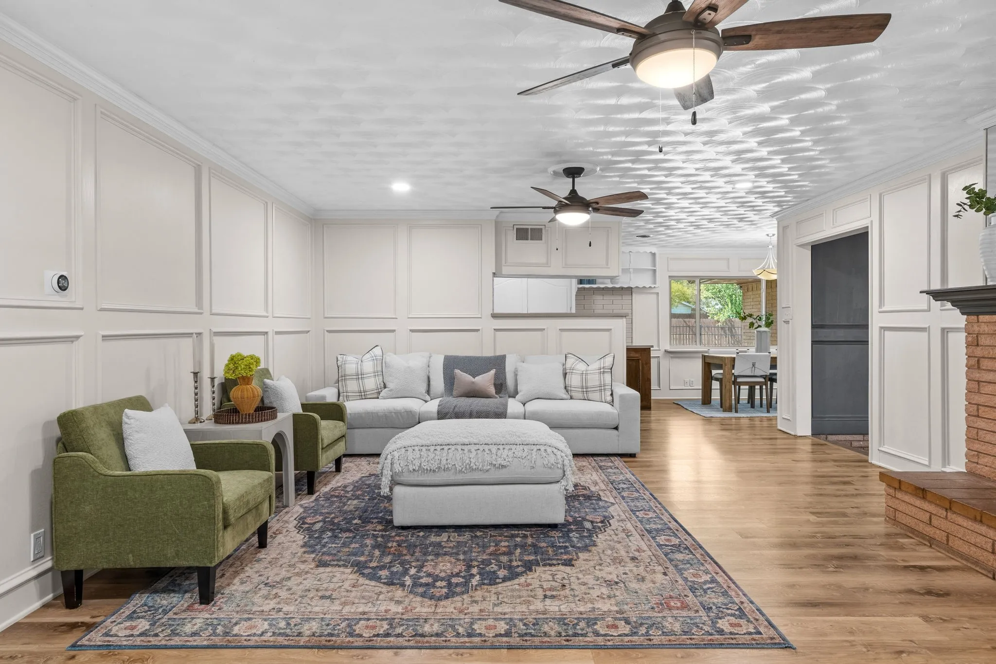 Hardwood flooring, crown molding, wainscoting, recessed lighting, and a brick fireplace
