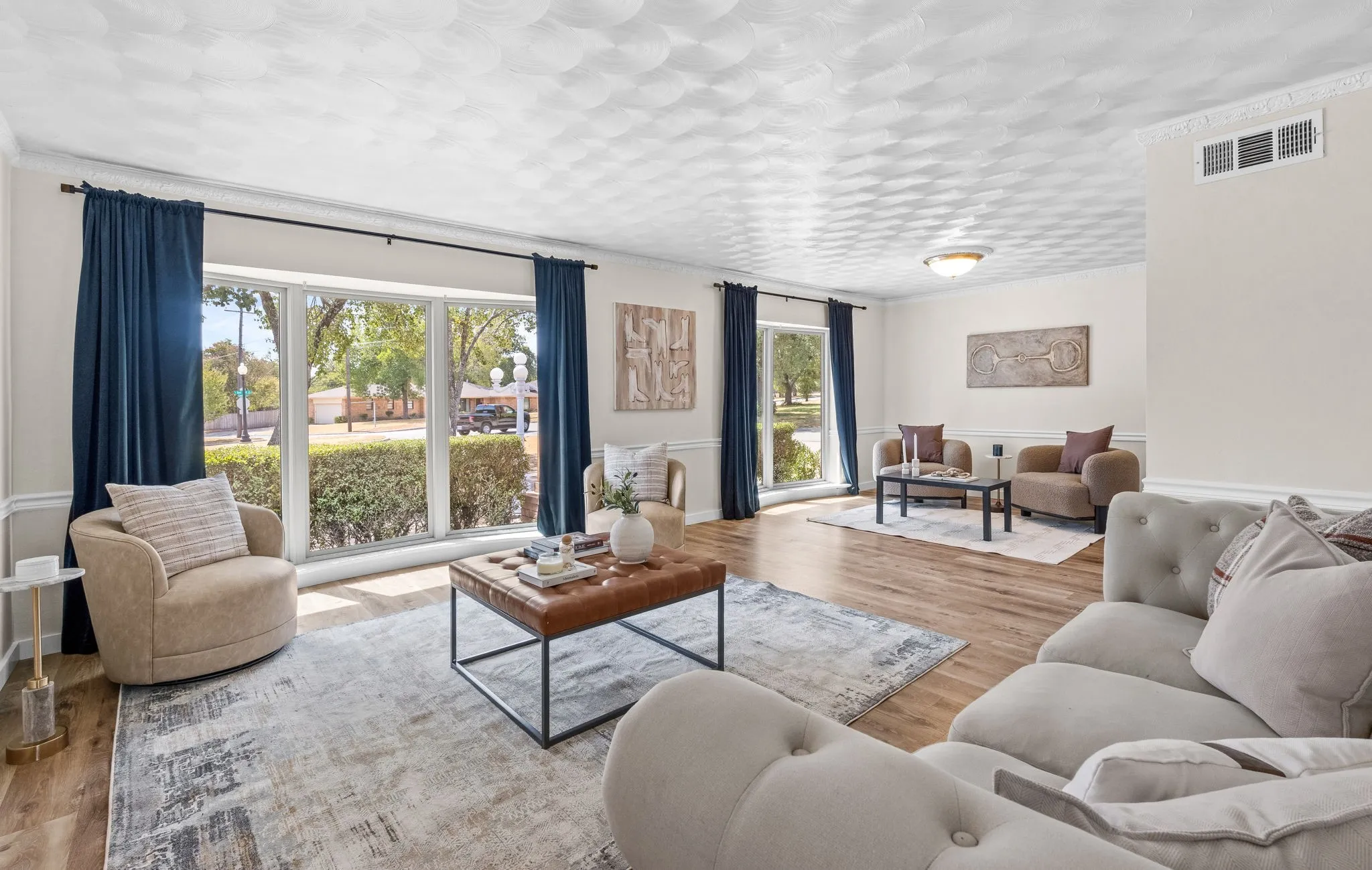 Spacious living area featuring wood-finish flooring, large bay windows, crown molding, and recessed lighting