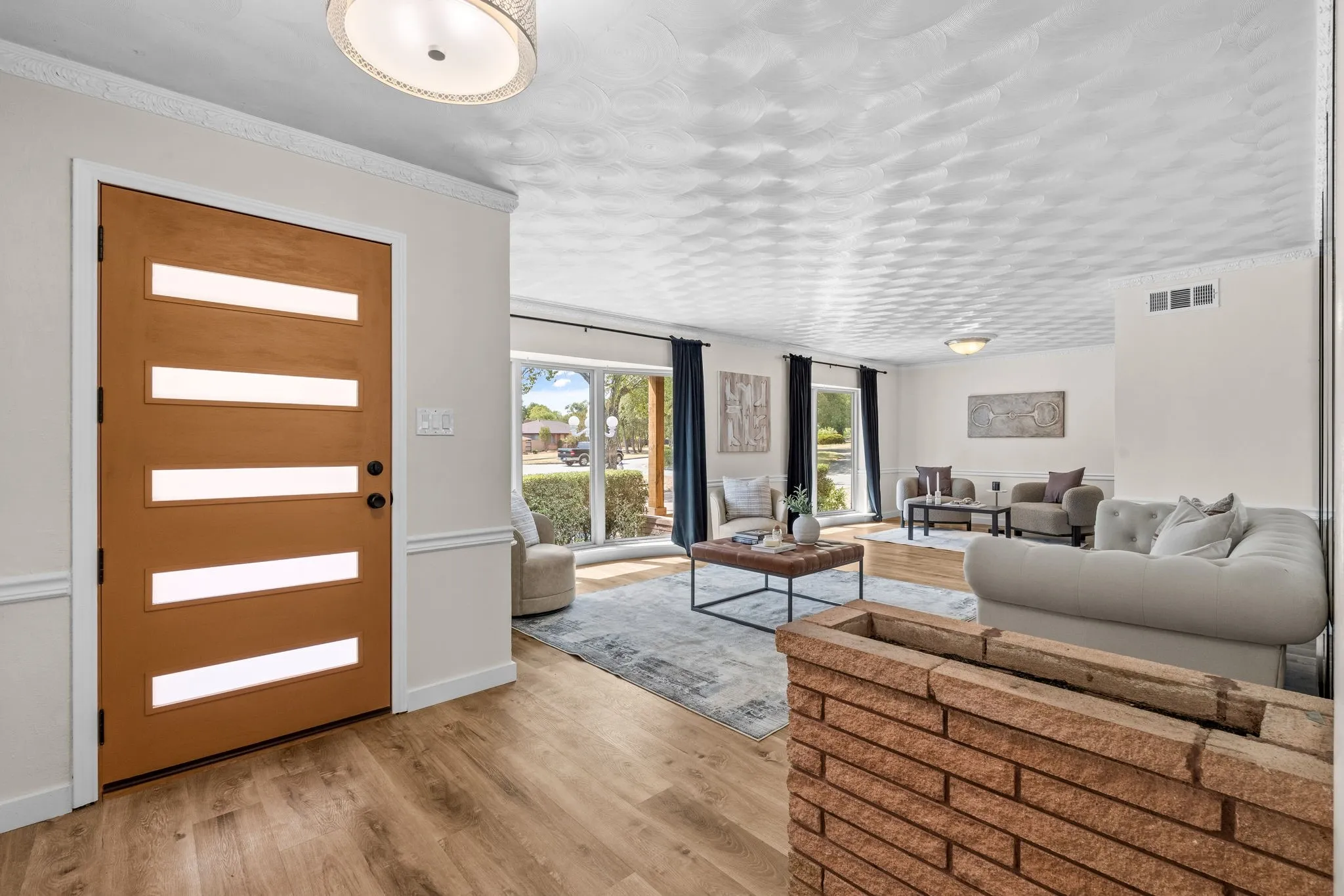 Contemporary wood-finish entry door with frosted glass panels, wood-finish flooring, and white baseboards