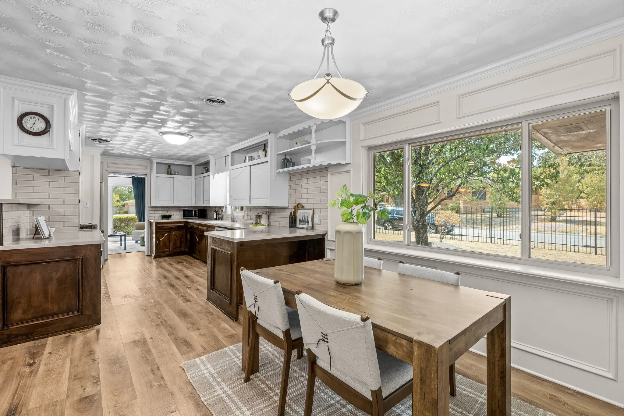 Kitchen featuring wood-finish flooring, two-tone cabinetry, subway tile backsplash, a center island, and a large picture window