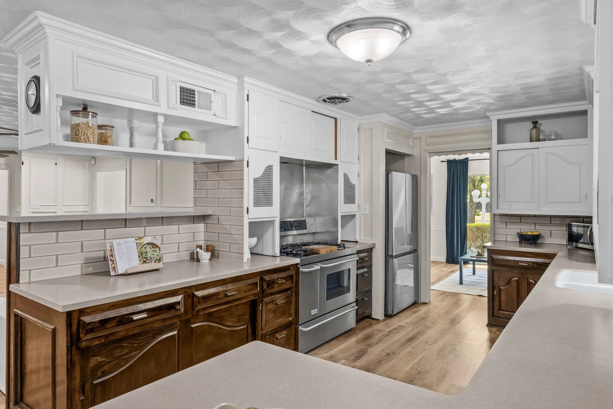 Kitchen featuring light-finish upper cabinetry, dark wood-finish lower cabinetry, light countertops, wood-finish flooring, and a subway tile backsplash