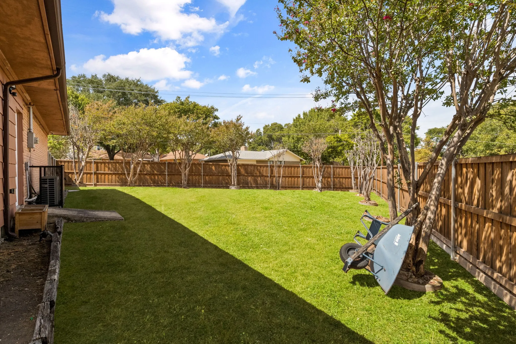 Expansive backyard featuring a lush lawn, wood fencing, and mature trees