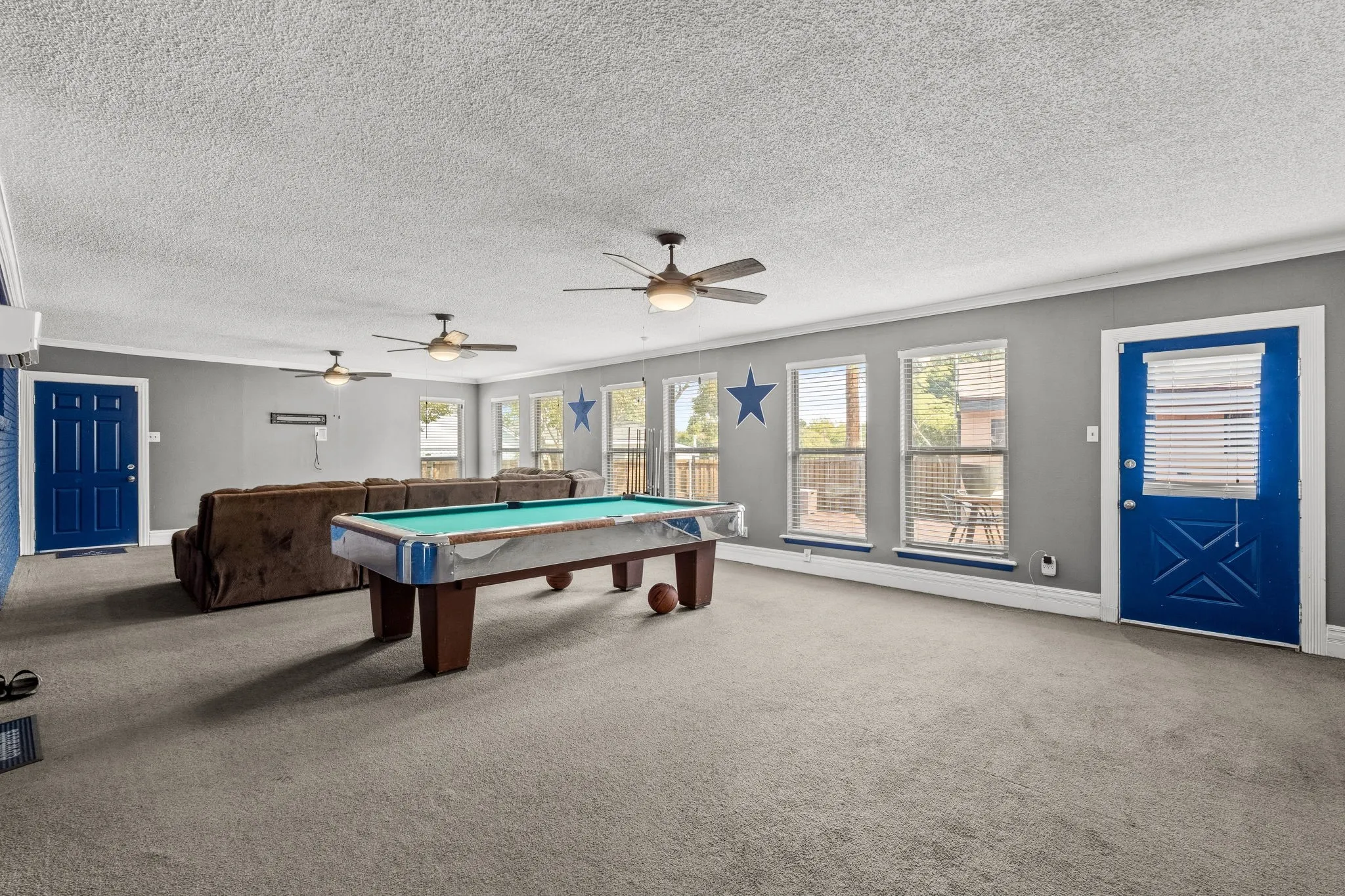 Expansive room with neutral carpeting, multiple ceiling fans, and a series of windows providing natural illumination