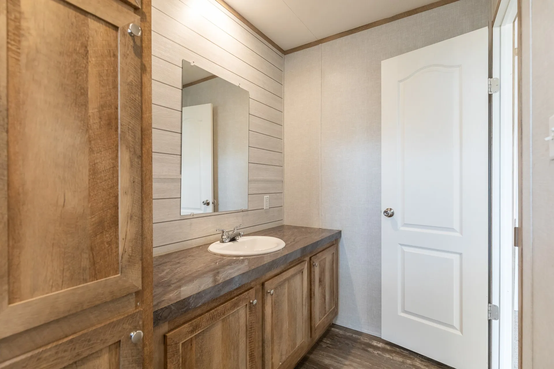 Vanity with wood-finish cabinetry, solid surface countertop, and an integrated basin sink