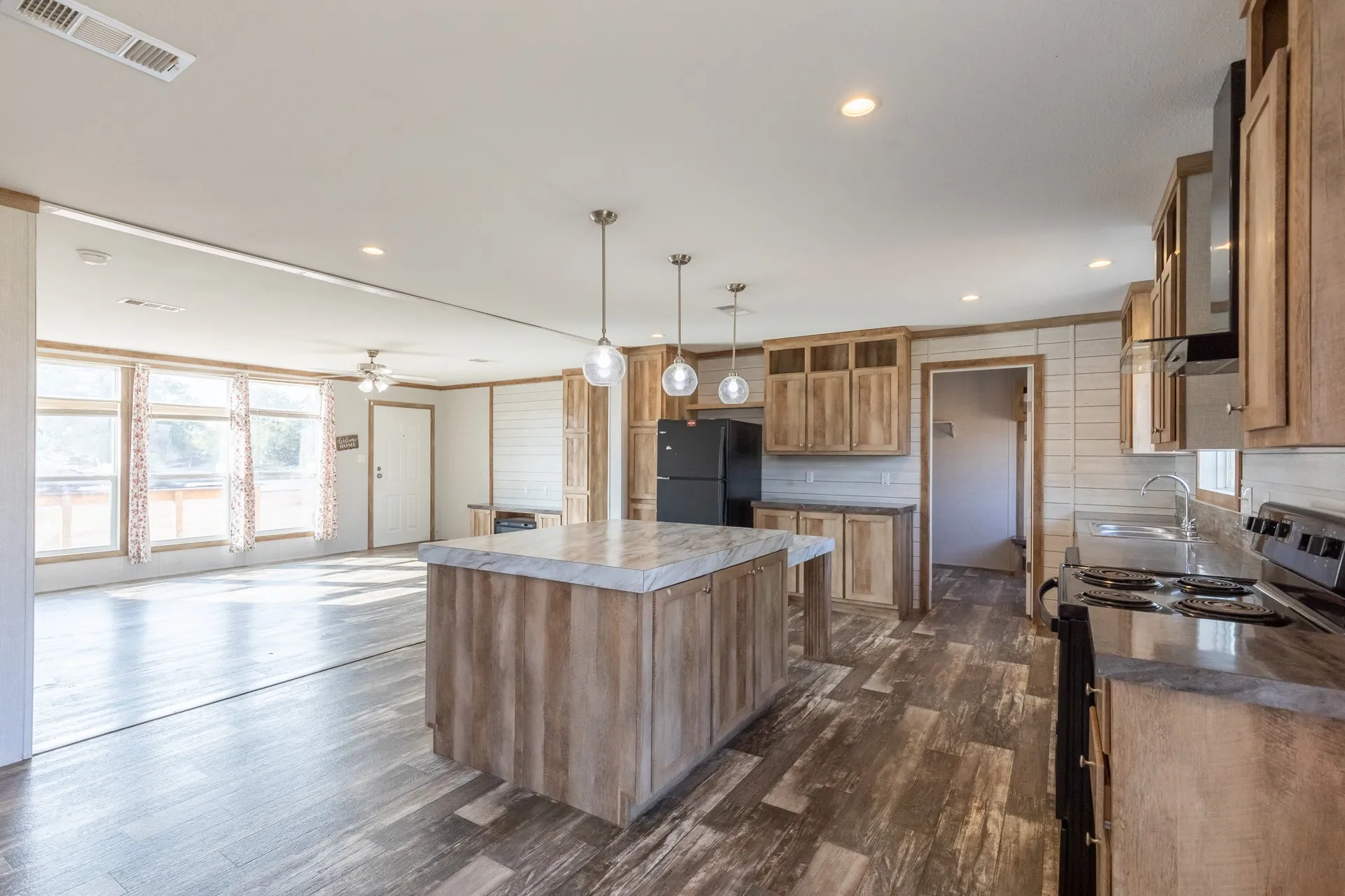 Kitchen featuring wood-finish cabinetry, stainless steel double-basin sink, dark countertops, and a stone-look tile backsplash