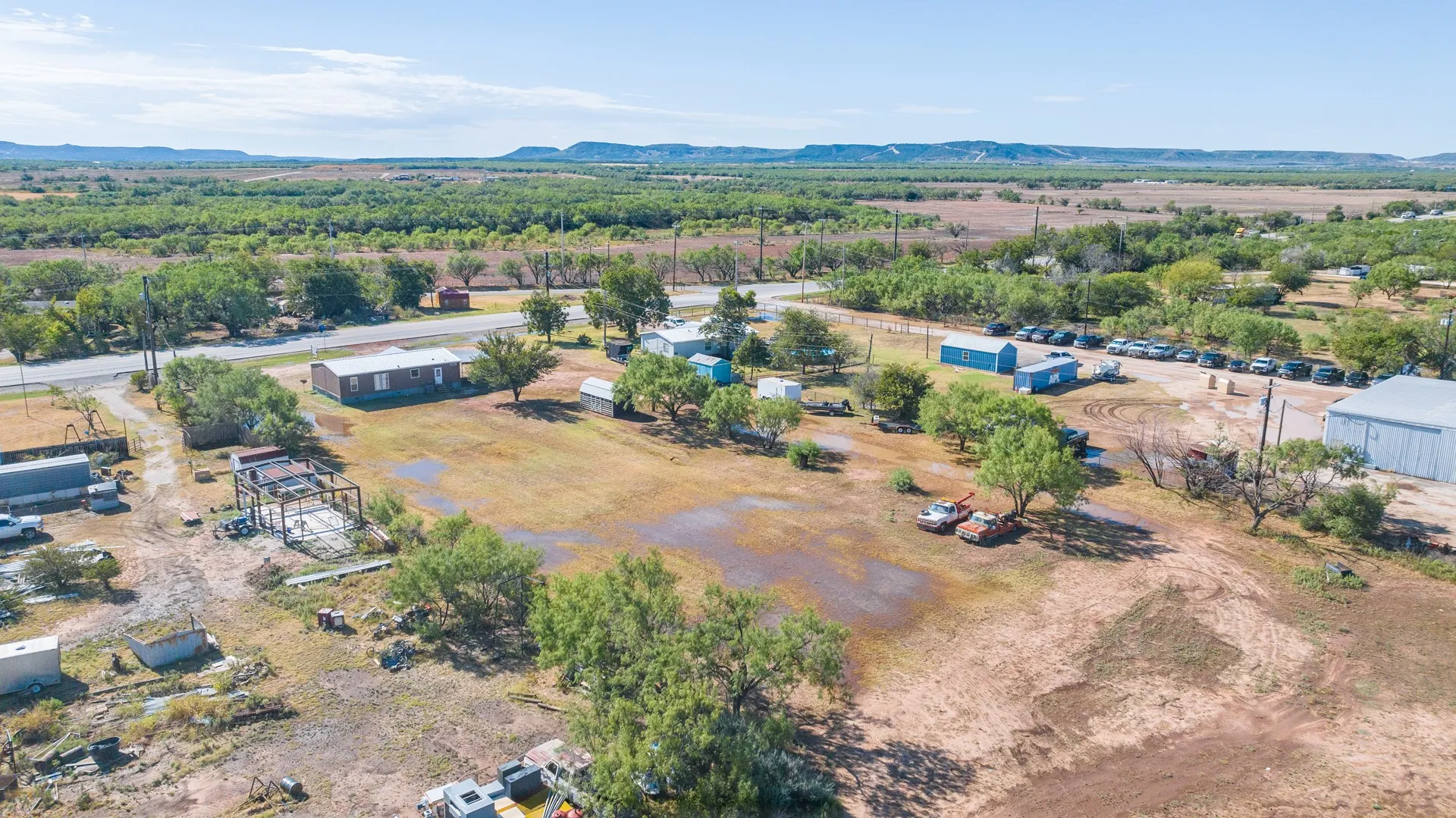 Expansive land parcel with multiple structures, including a single-story residence, a large outbuilding, and several smaller utility structures