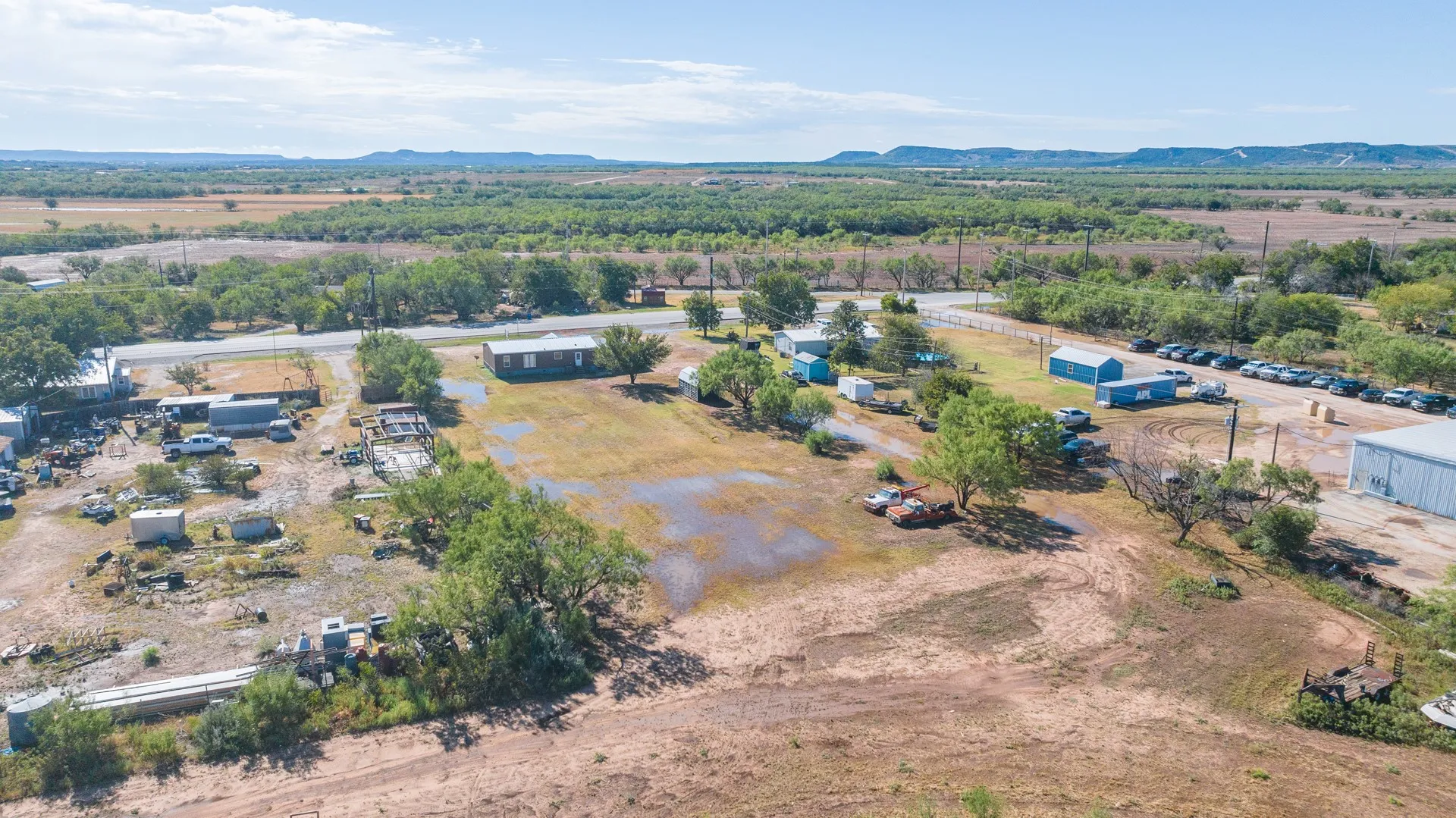 Expansive property featuring multiple structures, mature trees, and natural terrain