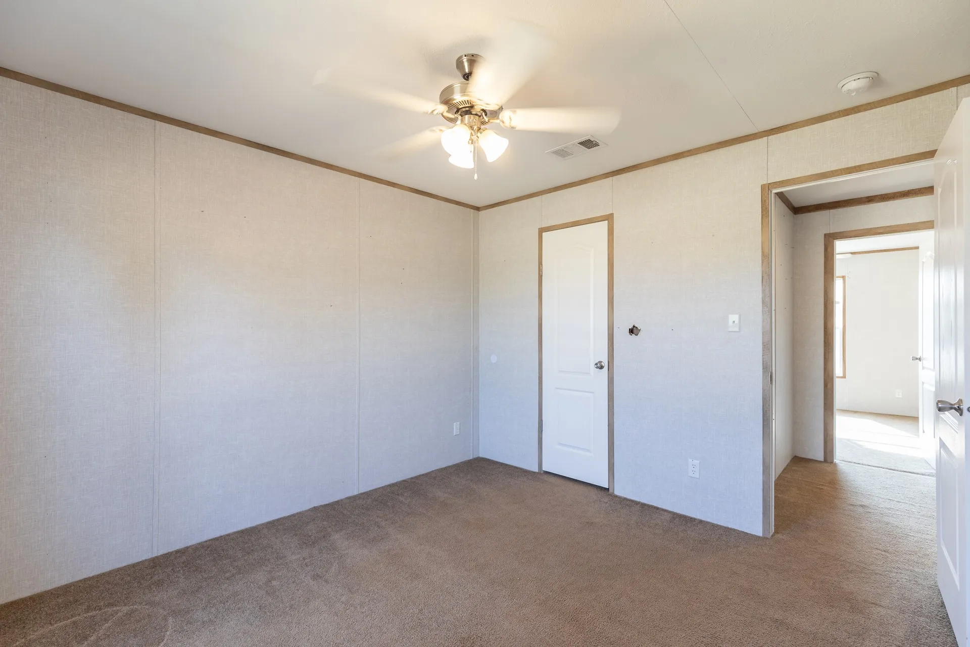 Wall-to-wall carpeting, ceiling fan with light fixture, and paneled walls with contrasting trim