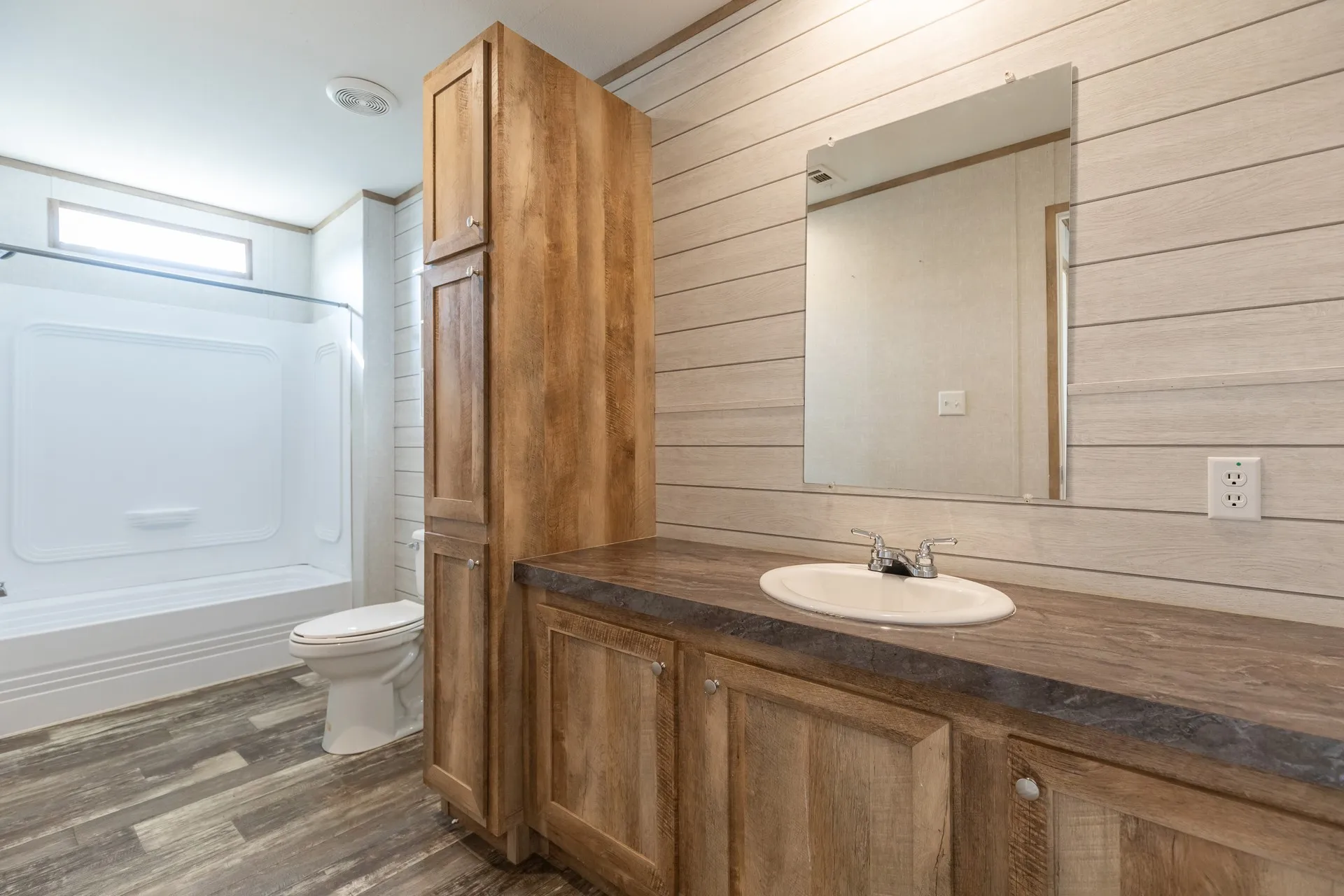 Wood-finish flooring, wood-finish vanity with an integrated sink, built-in storage cabinetry, and a shower-tub combination