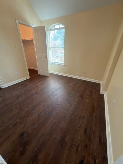 Wood-finish flooring, vaulted ceiling, arched window, and a built-in closet with shelving