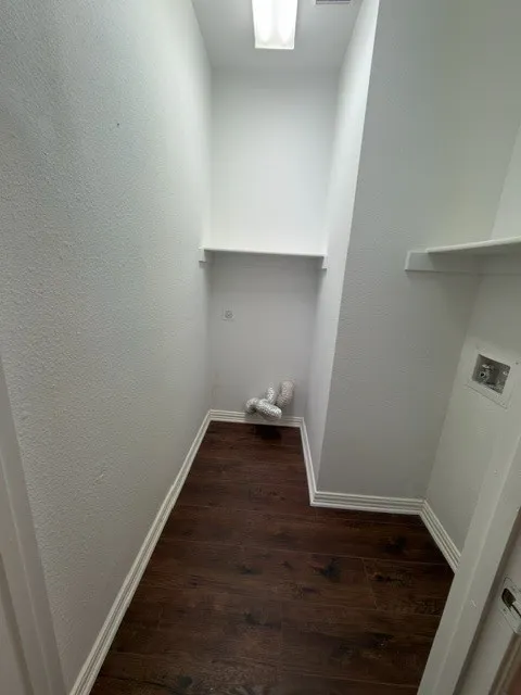 Utility closet with wood-finish flooring and built-in shelving