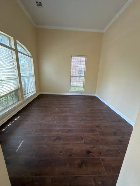 Dark wood-finish flooring, light tone wall paint, white crown molding, and white baseboards