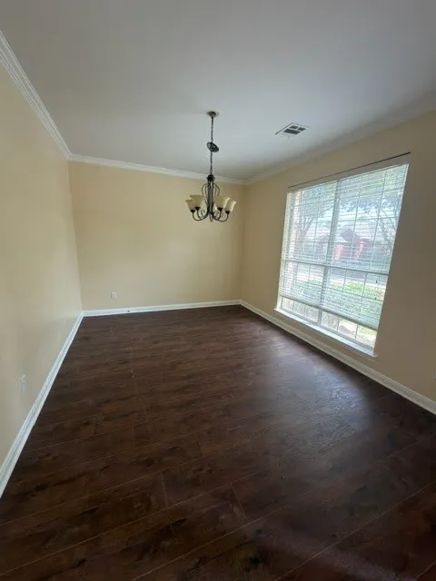 Dark wood-finish flooring with white trim, a multi-pane window, and a chandelier-style lighting fixture