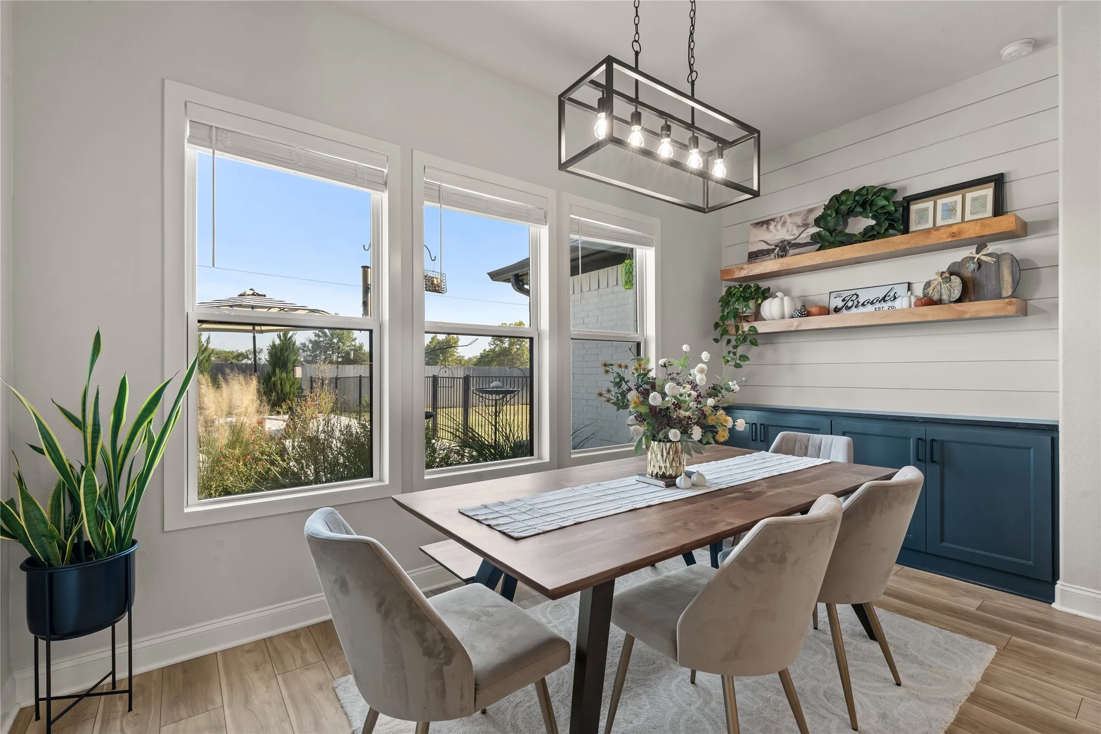Dining area featuring wood-finish flooring, multiple windows, a linear chandelier, built-in cabinetry, and open shelving