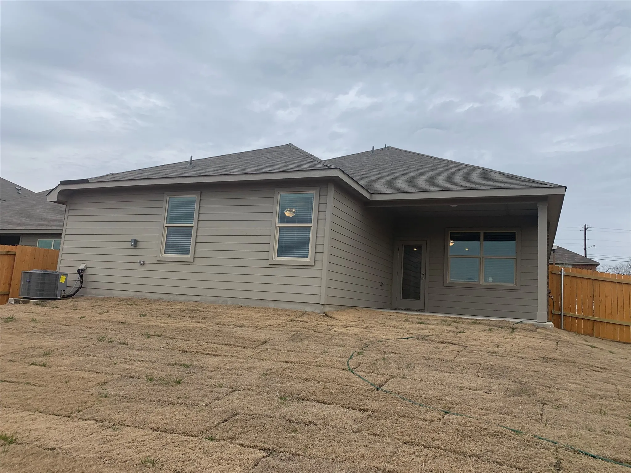 Rear exterior with horizontal siding, a covered patio, and a sloped lawn