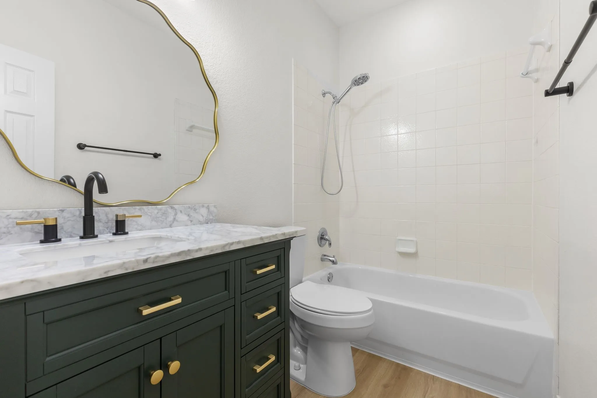 Deep green vanity with gold-finish hardware, white marble-pattern countertop, and a contemporary gold-finish mirror