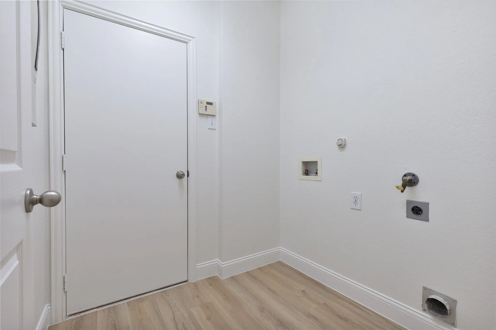 Dedicated laundry area with wood-finish flooring and white walls