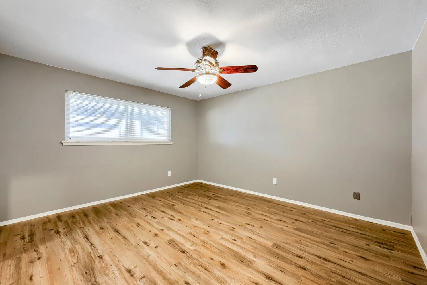 Wood-finish flooring, neutral wall paint, and a ceiling fan with integrated lighting