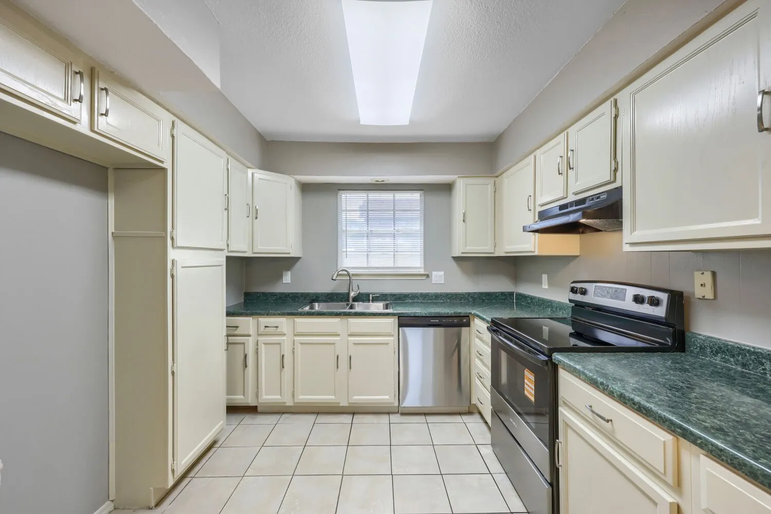 Kitchen featuring white cabinetry, green patterned countertops, stainless steel dishwasher, black electric range, and light-toned tile flooring