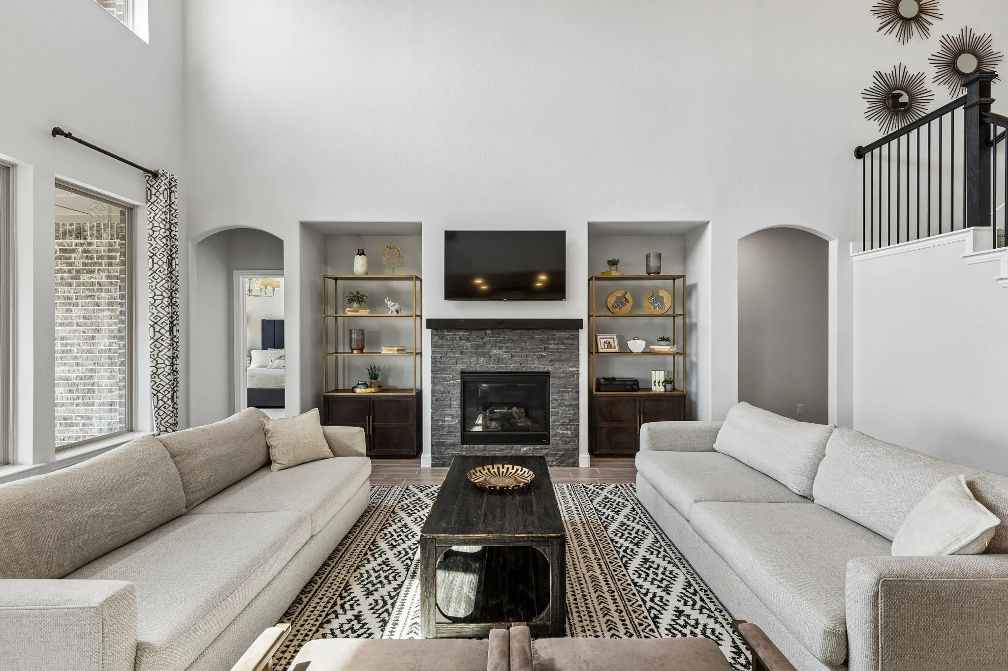 Sophisticated living room centers around a handsome fireplace with custom-style built-ins, complemented by a generous seating area, designer finishes, and dramatic ceiling height.