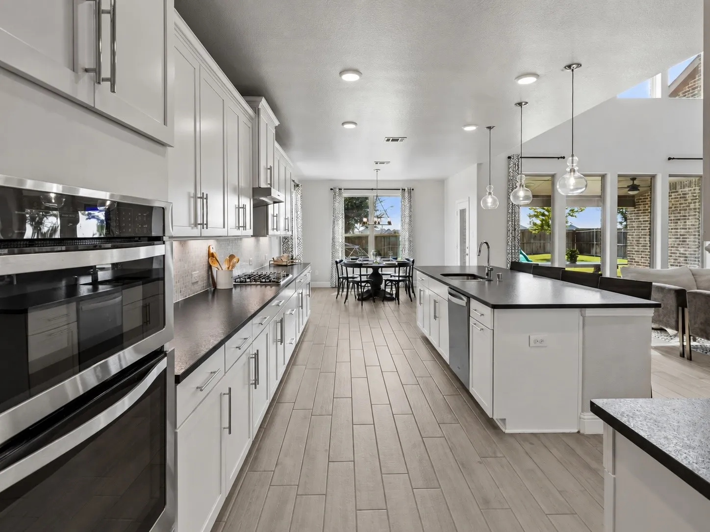 Bright and beautifully appointed kitchen opens naturally toward the breakfast and living spaces, creating a seamless everyday gathering area with extensive cabinetry, pendant lighting, and generous prep surfaces.