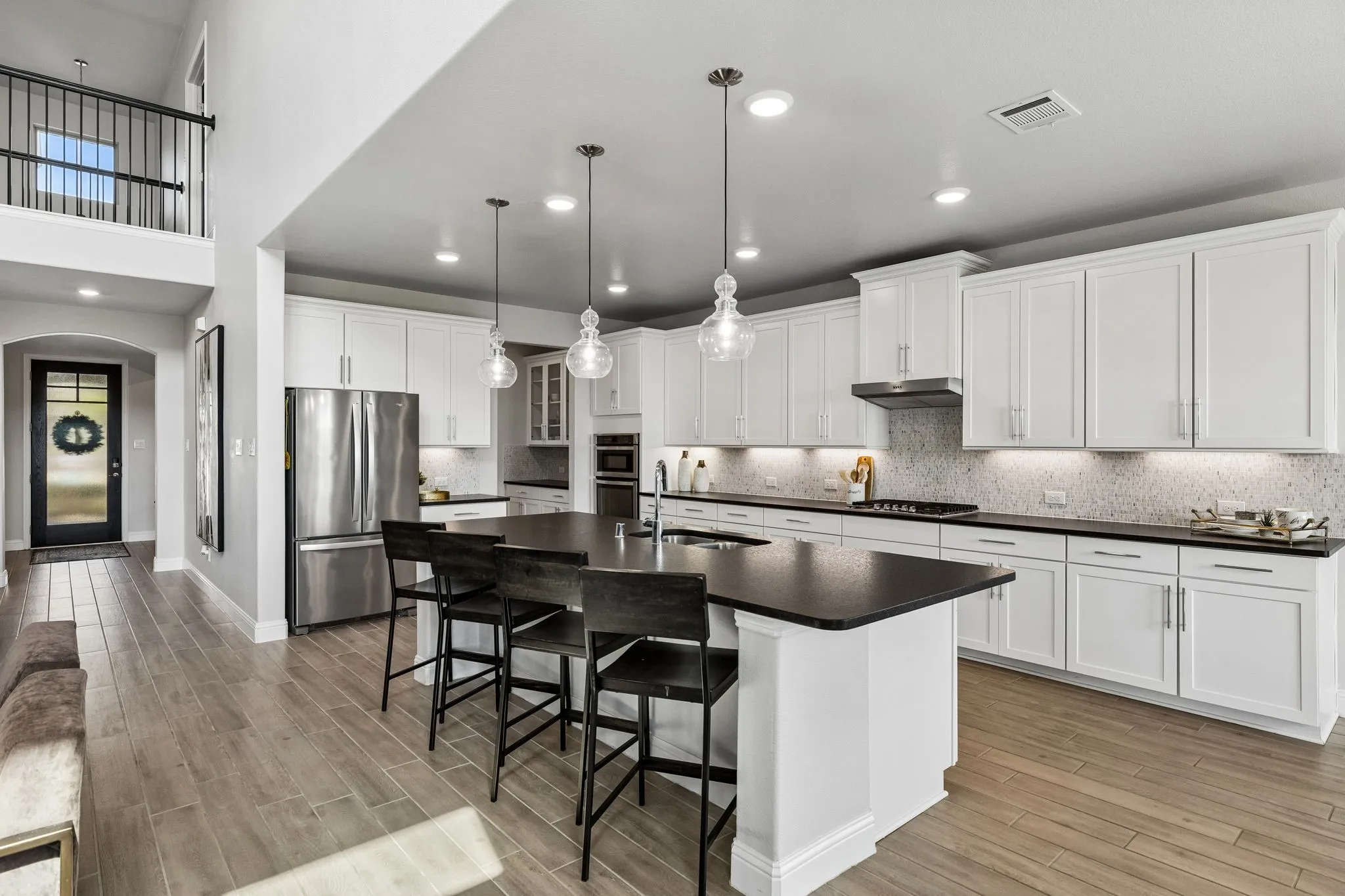 This kitchen has exceptional functionality and connection to the living spaces, with extensive cabinetry, oversized island, pendant lighting, and abundant natural illumination.